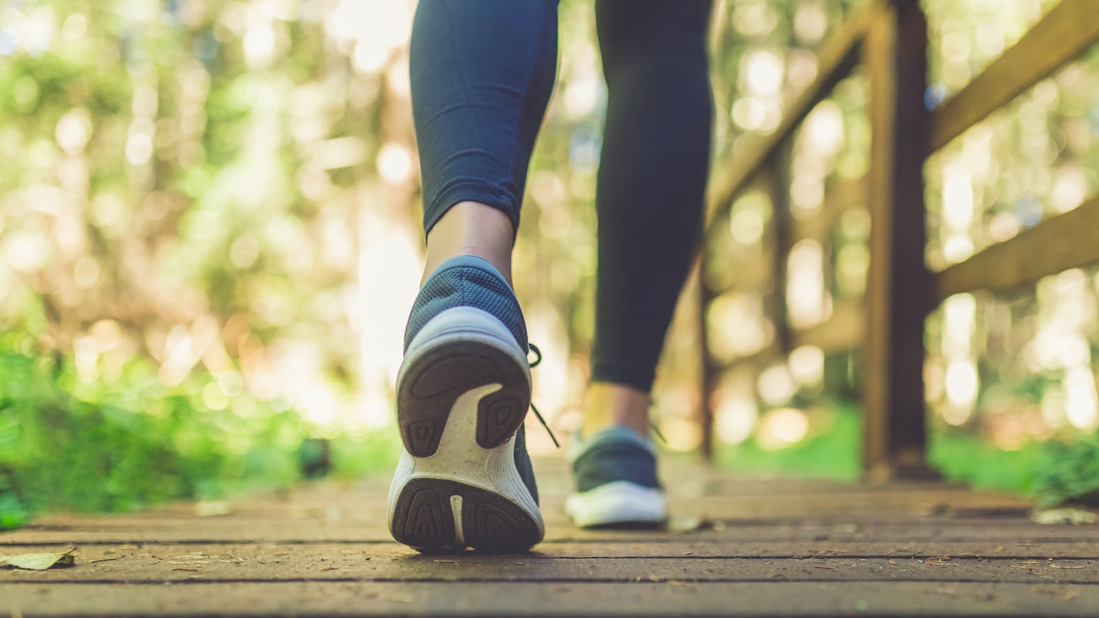 Feet walking on a wooden bridge in the woods