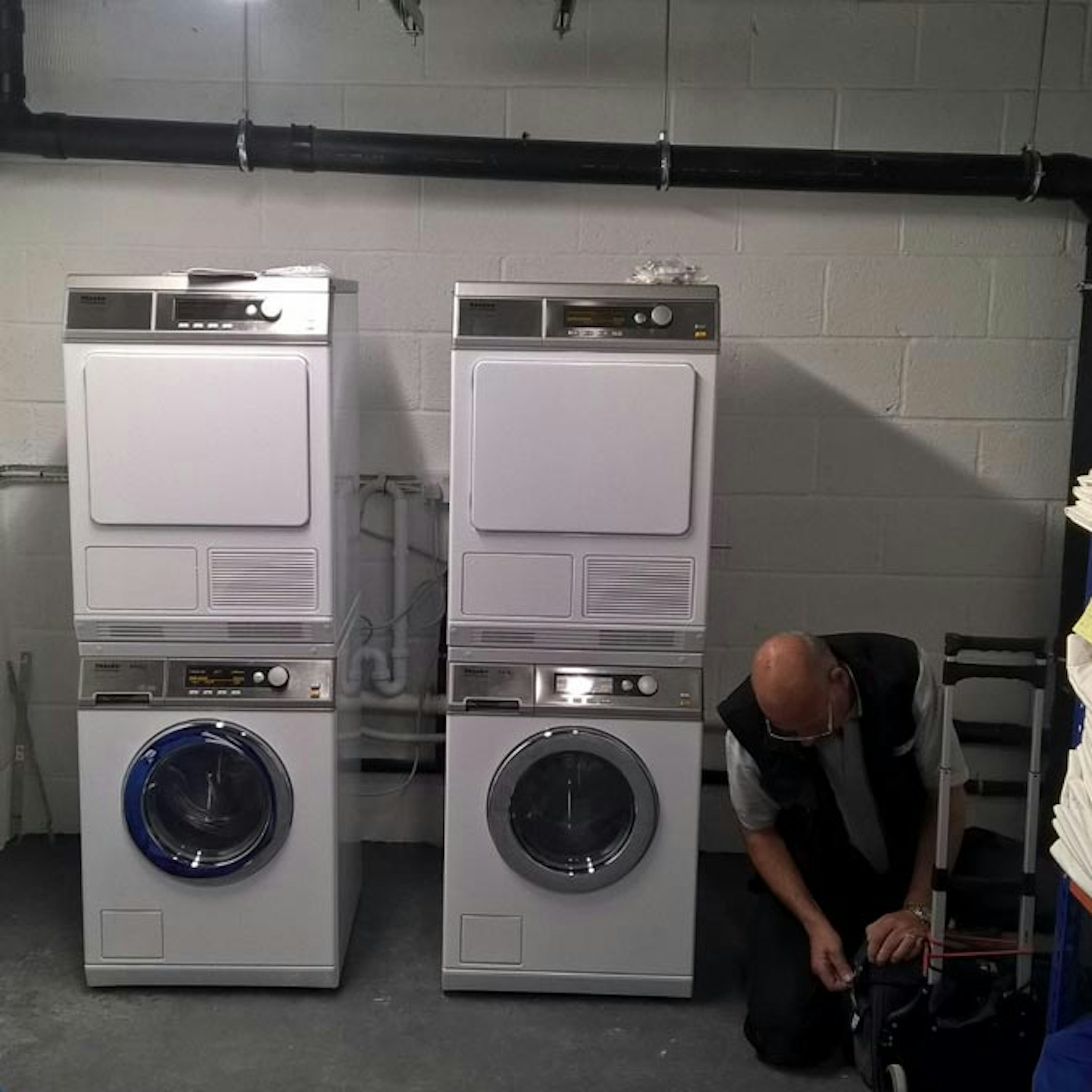 Engineer kneeling next to commercial washing machines