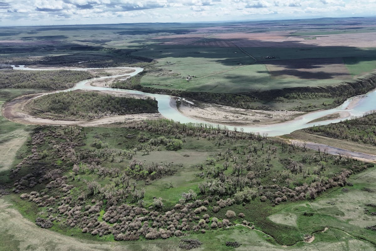 Vue aérienne d'un paysage traversé par une rivière et ombré par les nuages.