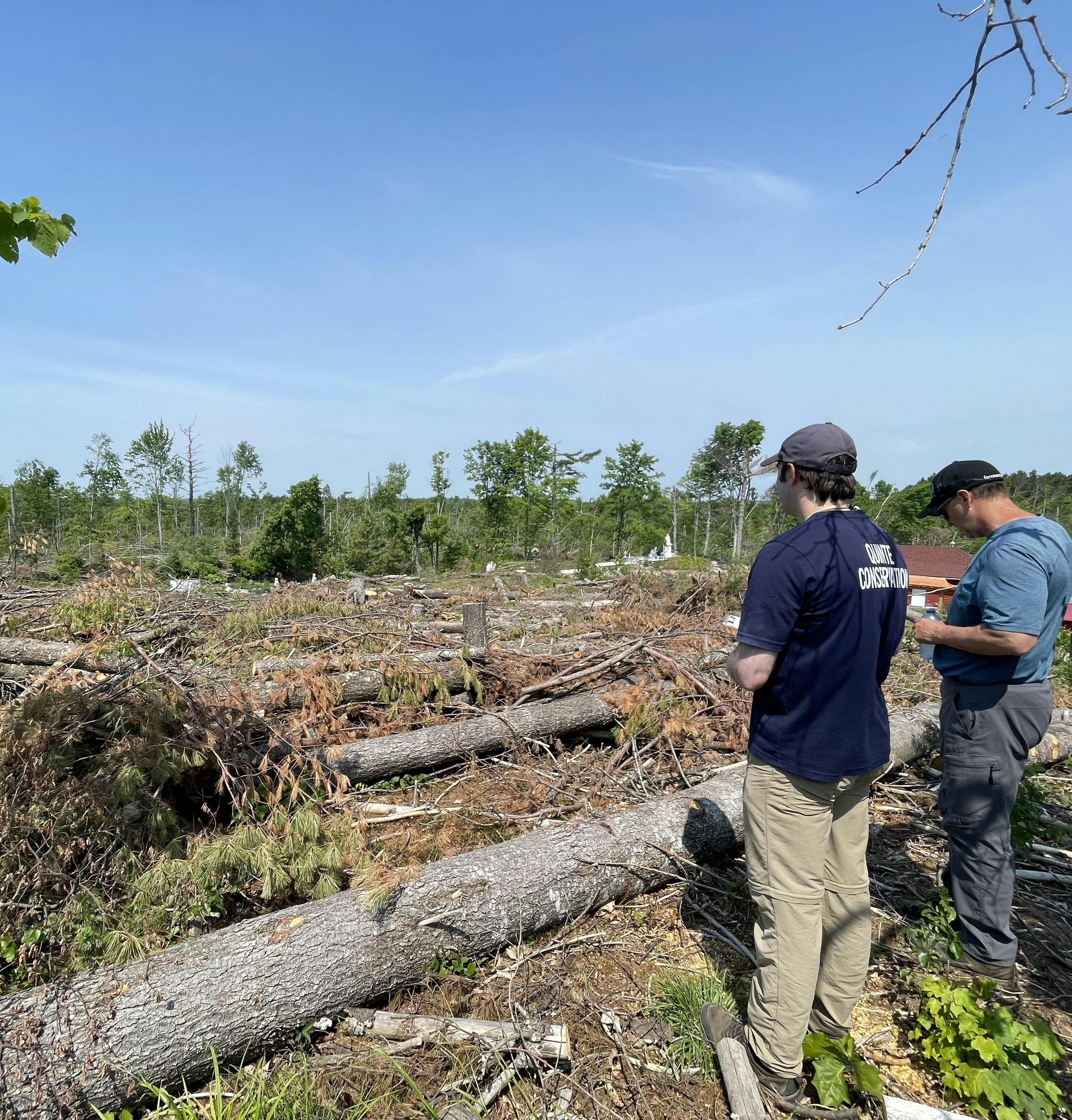 Two men standing in front of tornado damage