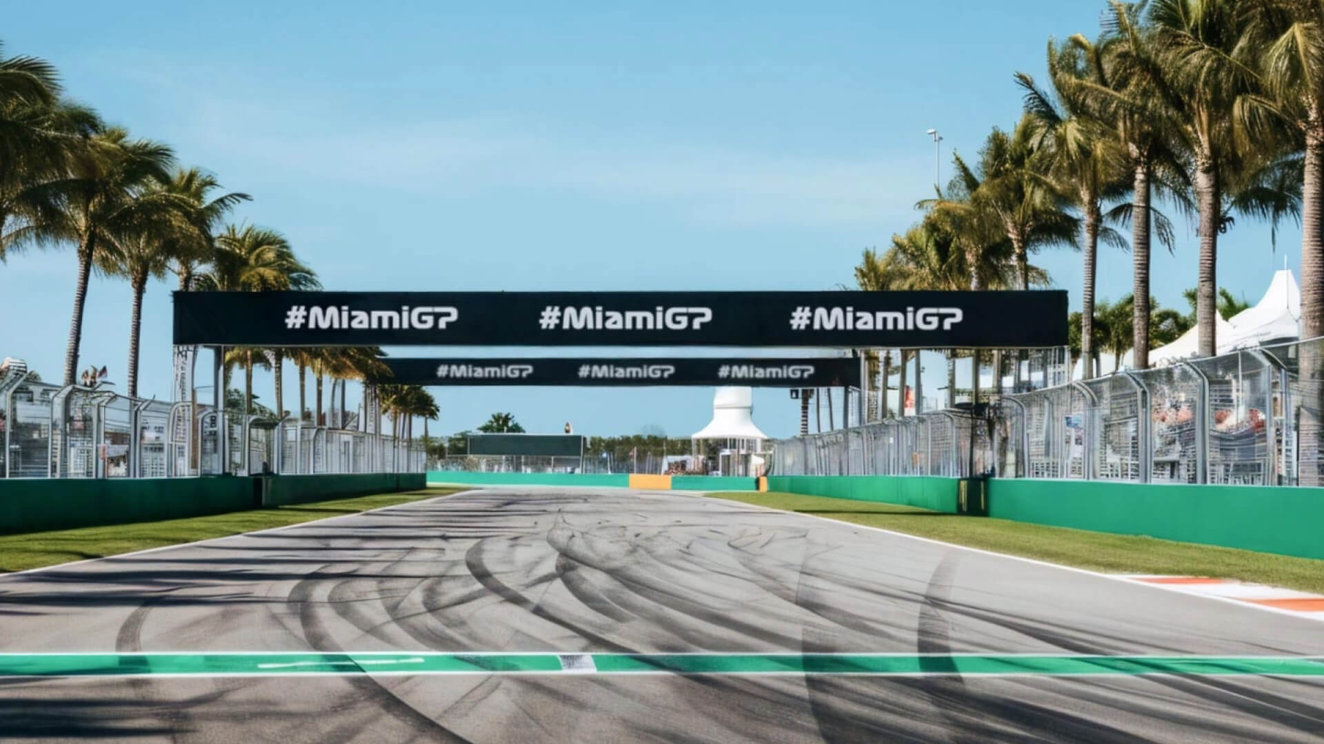 Formula 1 track in Miami with palm trees and overhead F1 banner.