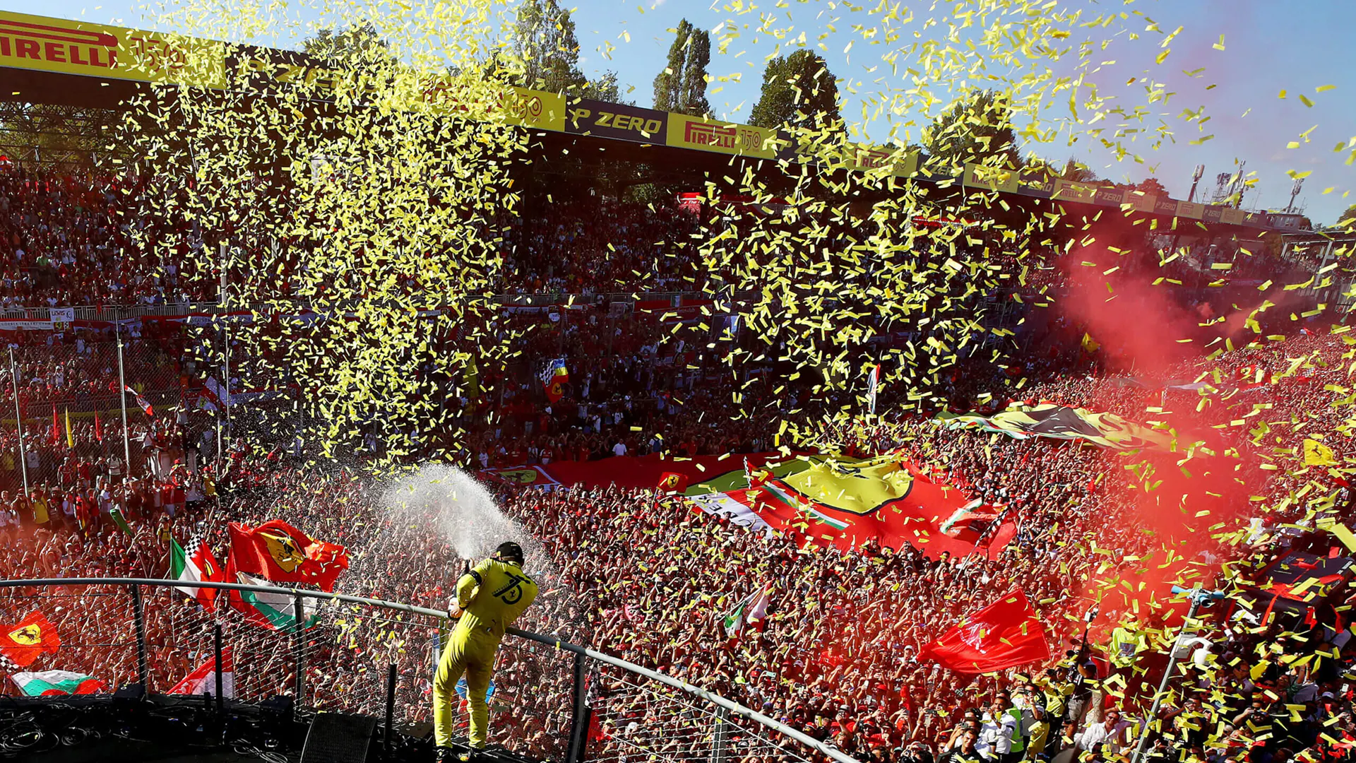 Leclerc celebrating a 2024 victory on the podium, with a crowd of Ferrari fans.