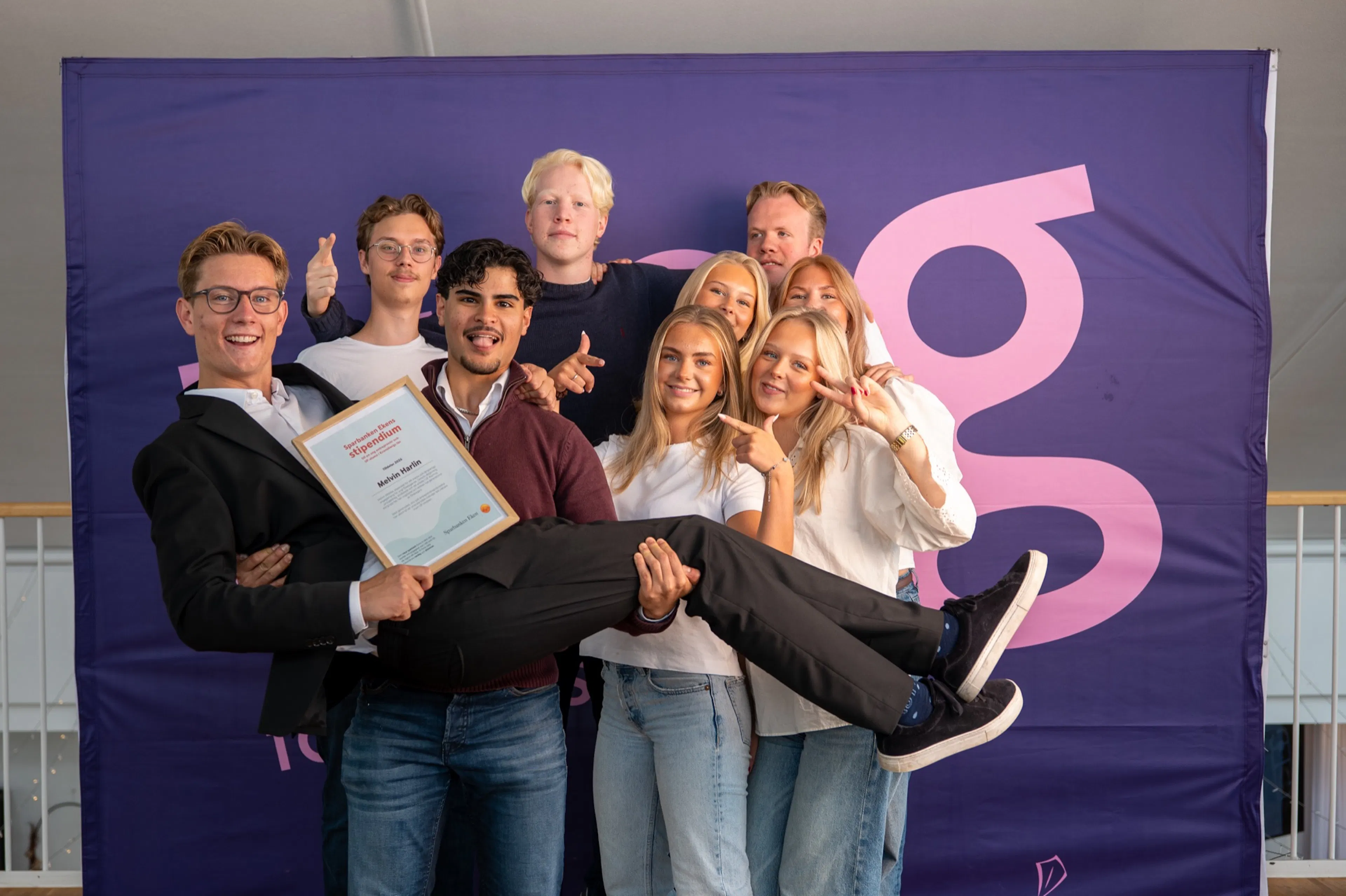 Vinnarna firar med diplomet framför fotoväggen