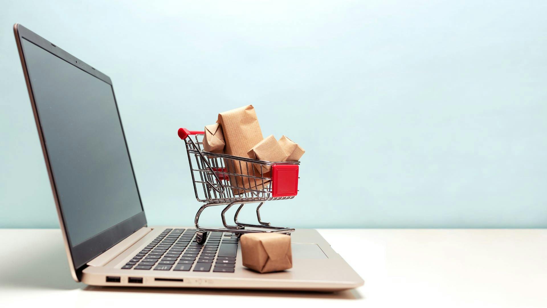 A shopping cart on top of a laptop. 