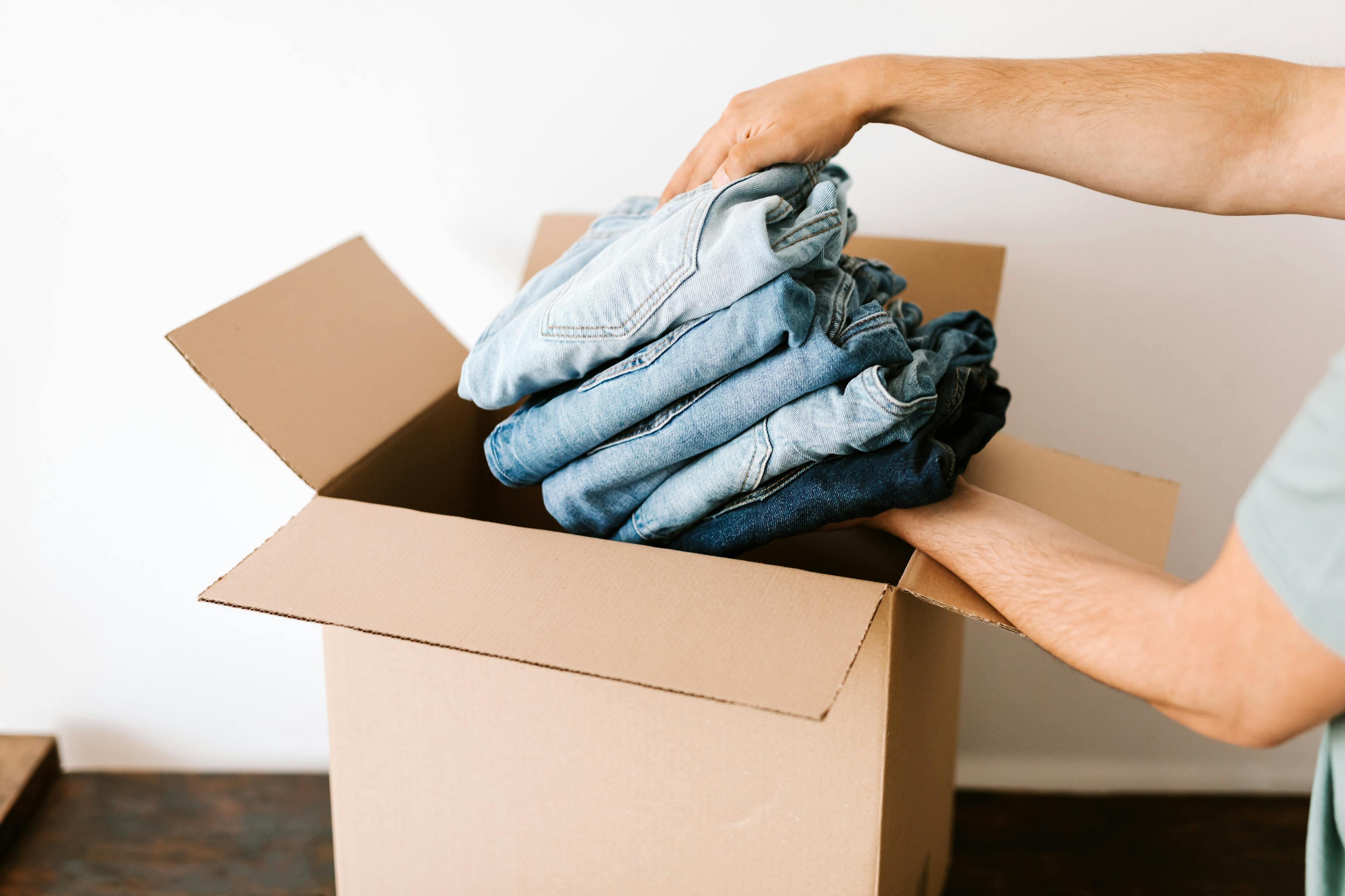 A man packing clothes into a shipping package.