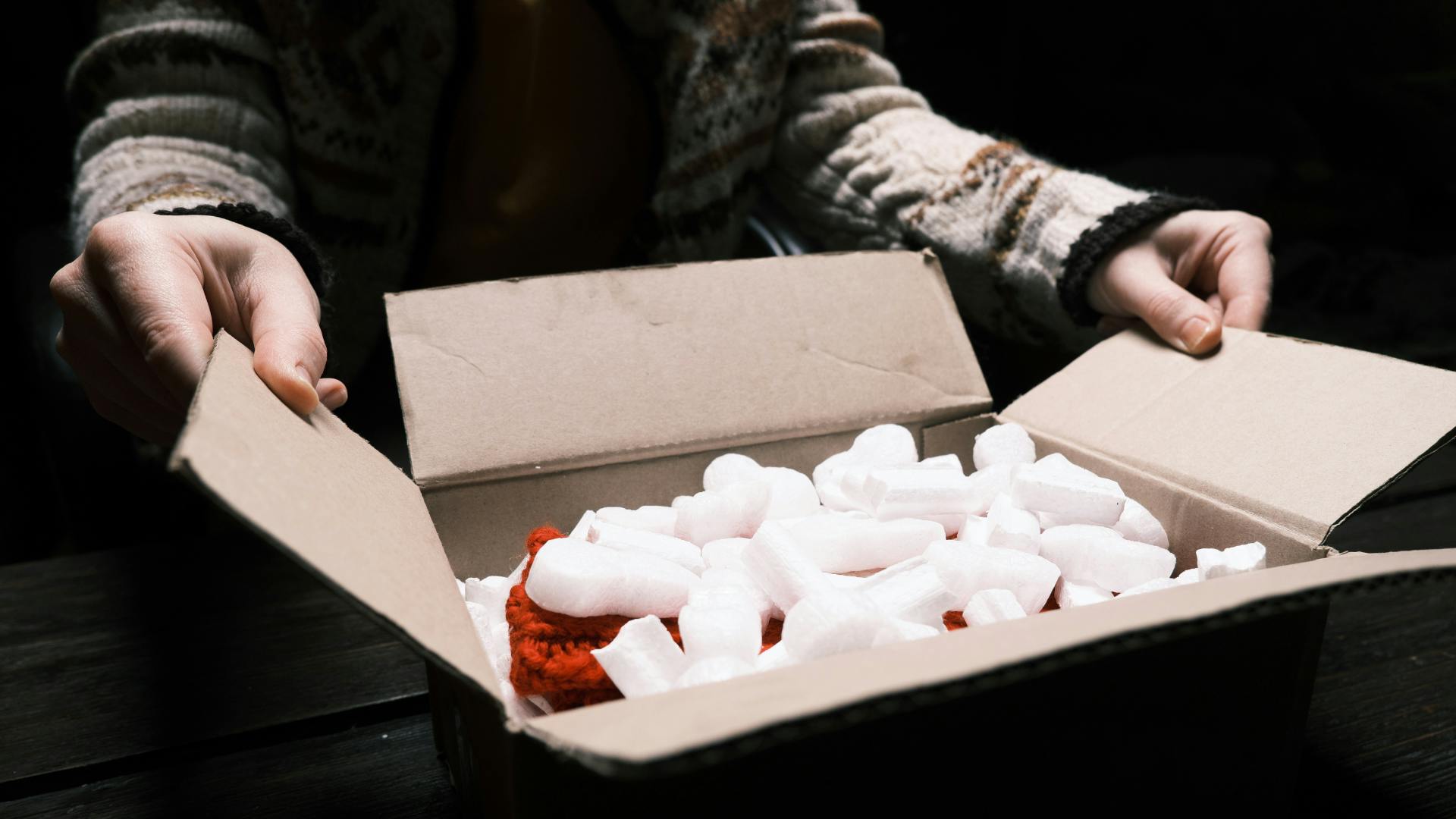 A man closing a shipping package. 