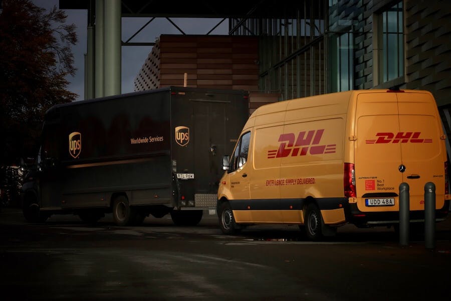 UPS and DHL Express delivery trucks on a street UPS and DHL Express delivery trucks on a street