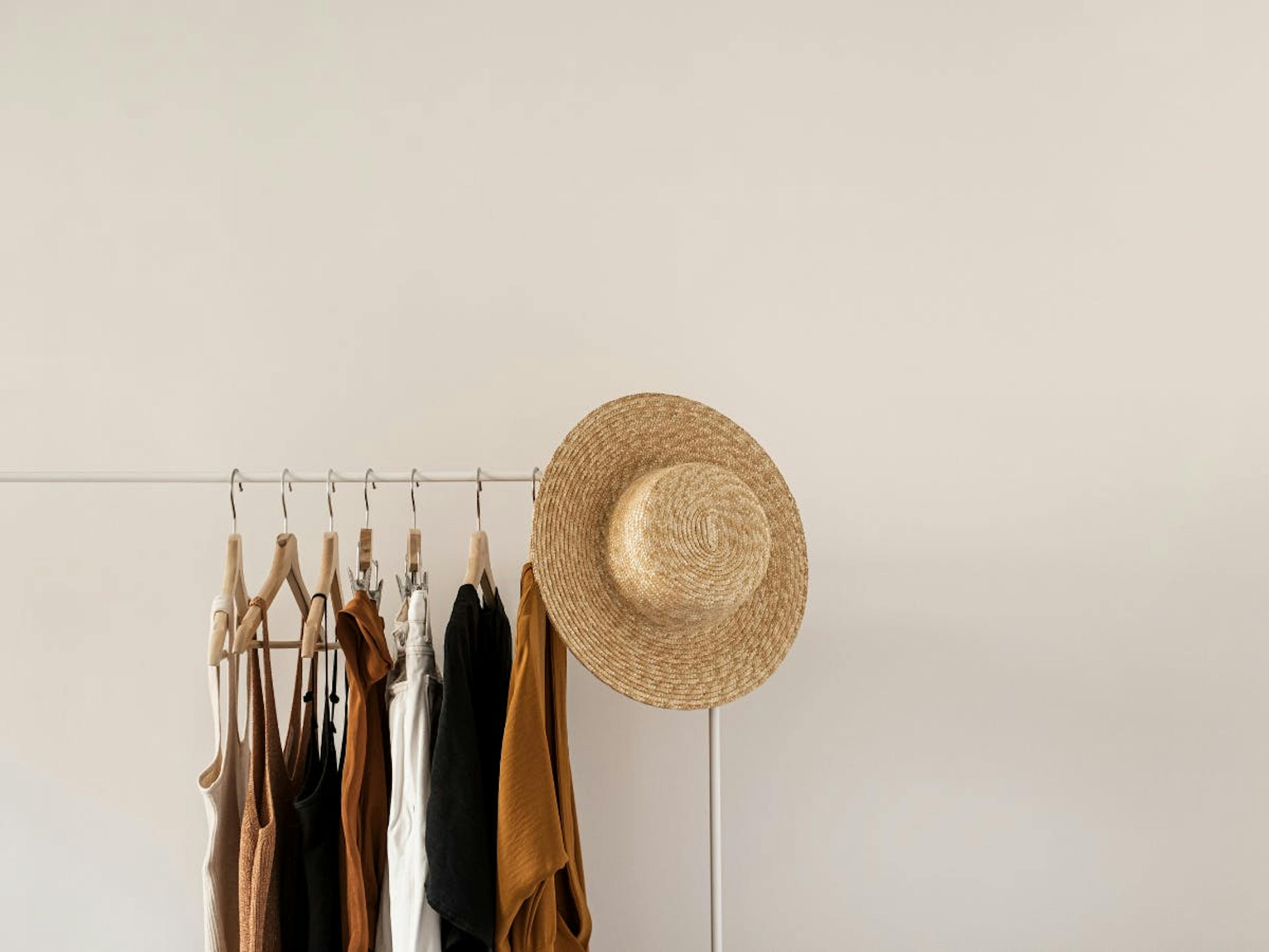 A clothing rack with clothes and a hat. 