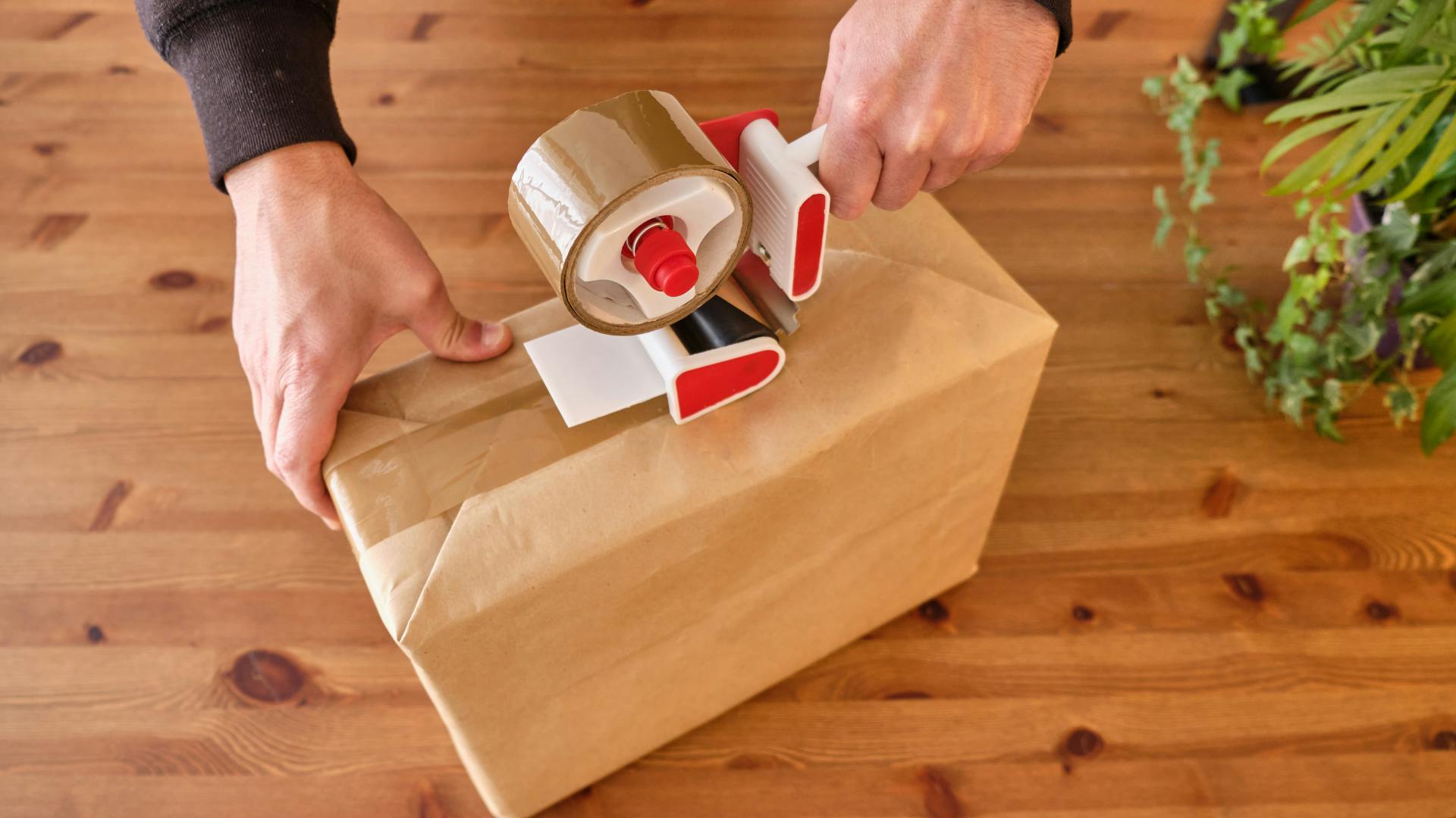 A person preparing a shipping box on a wodden surface to ship the package internationally. 