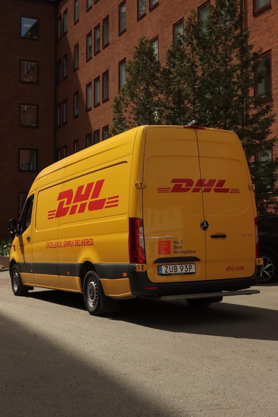 DHL Express truck driving on front street near city