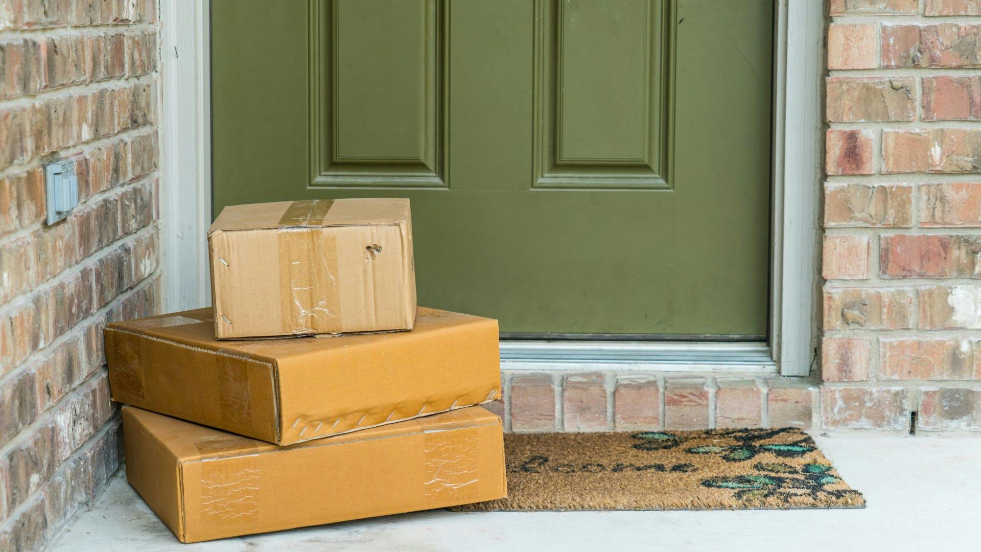 3 packages stacted over each other on the door of a house. 