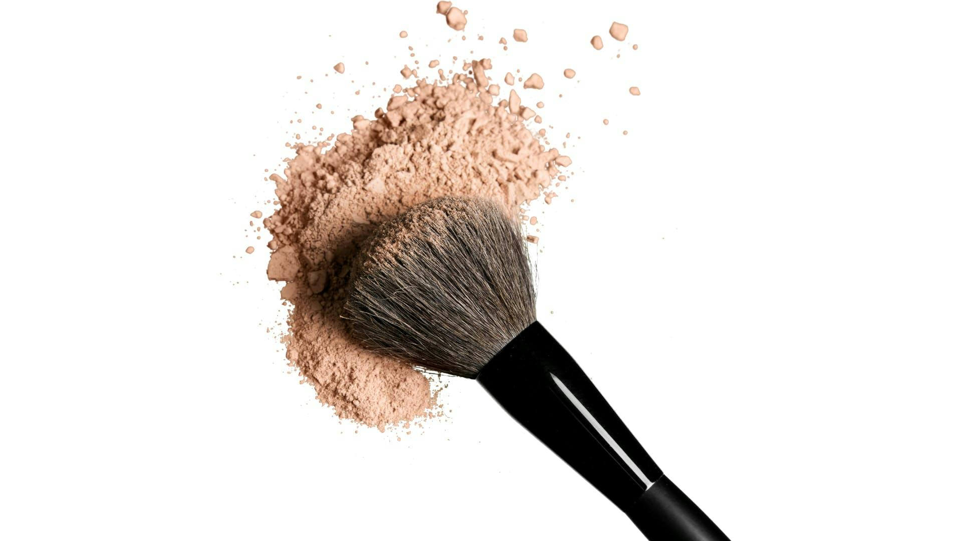 A make-up brush with make-up scattering around. 