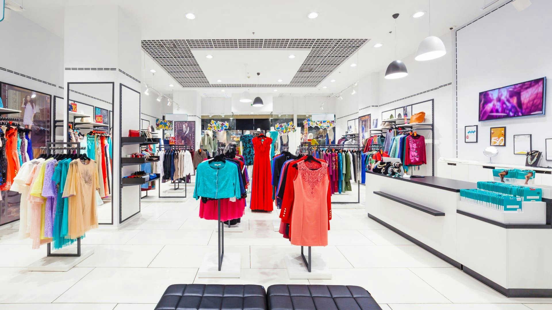 A part of the store with check-out and a few clothing racks. 