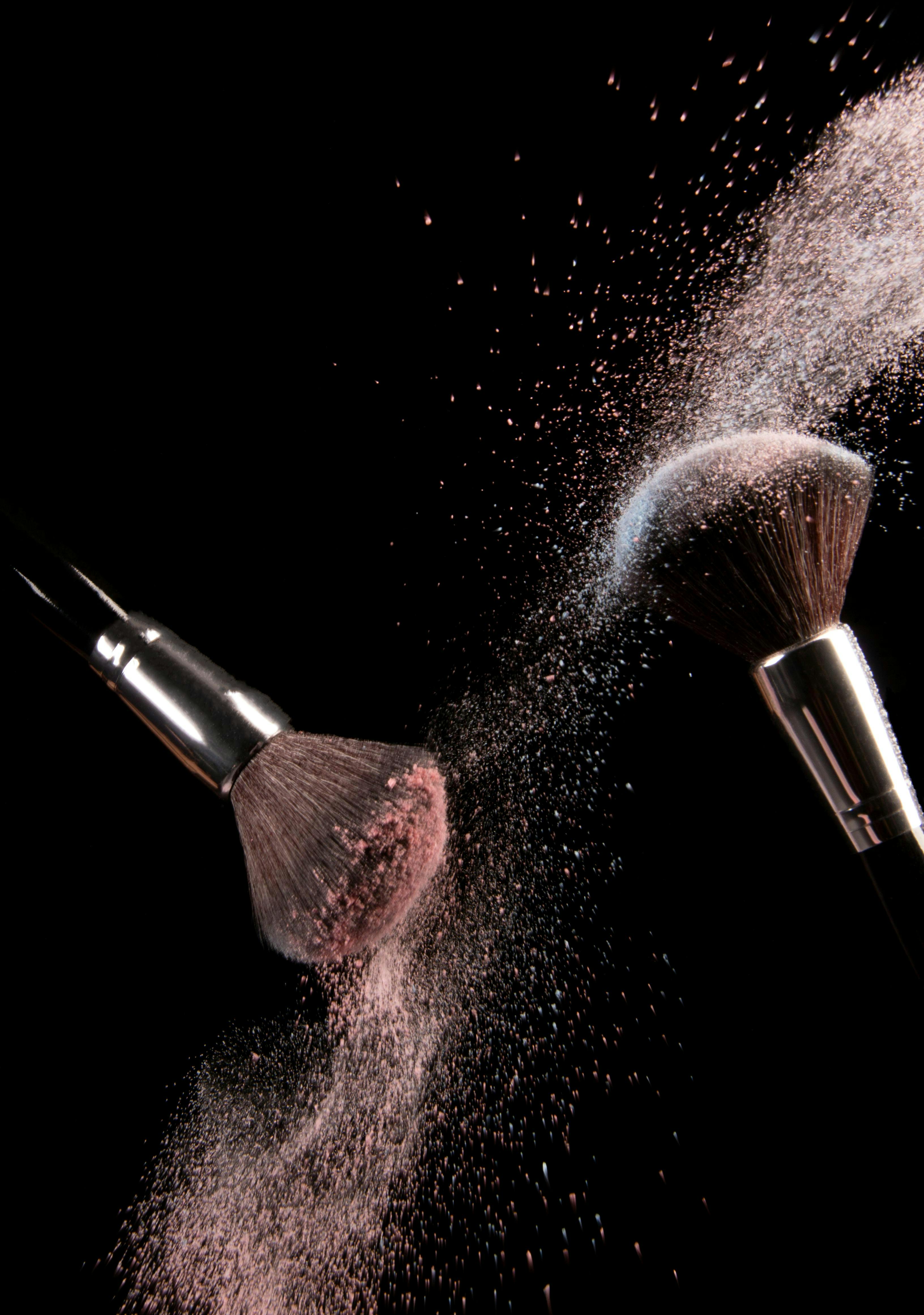 Two make up brush with powder on black background. 