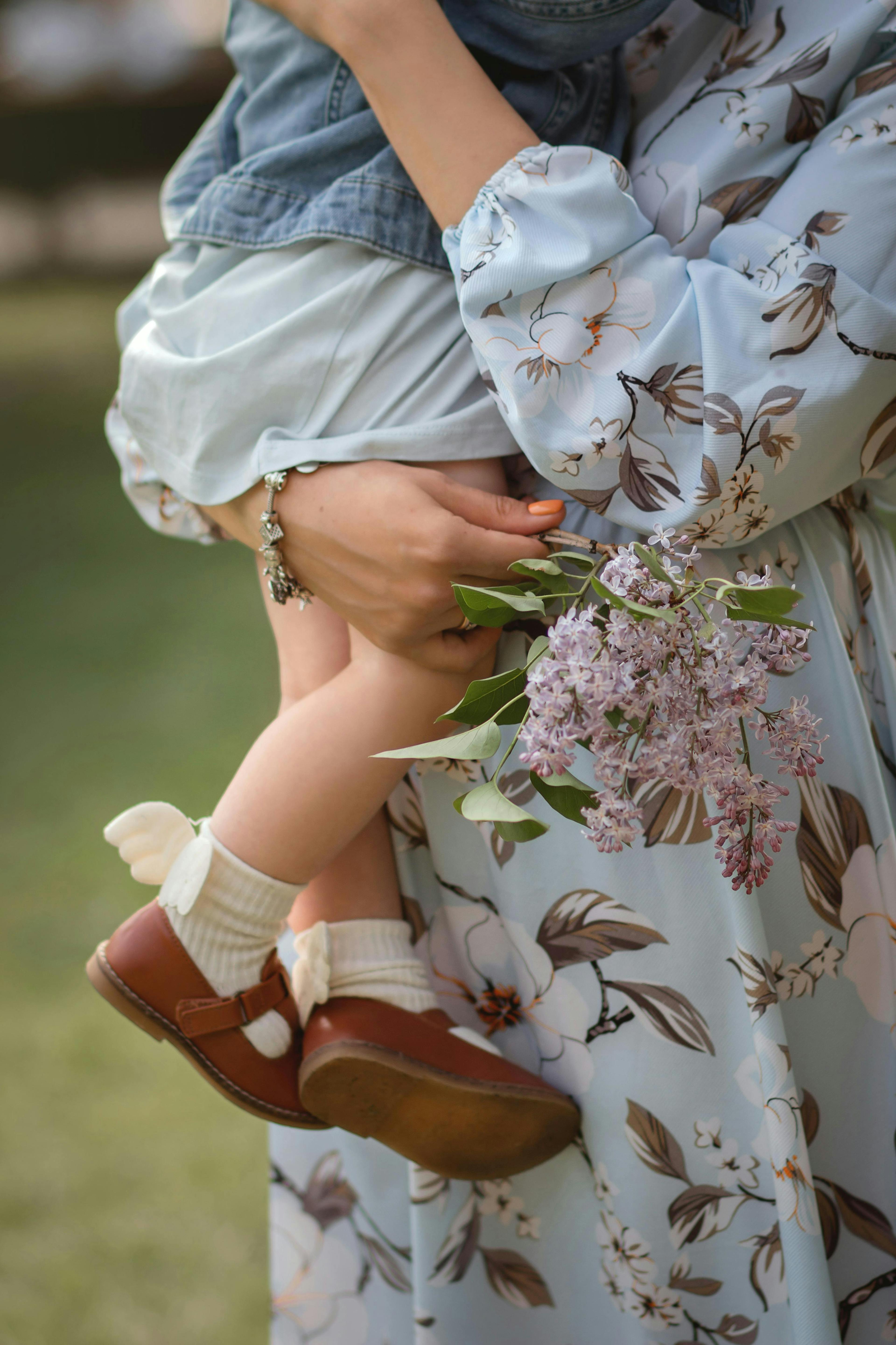 A mother carrying her baby while wearing a fashionable summer dress. 