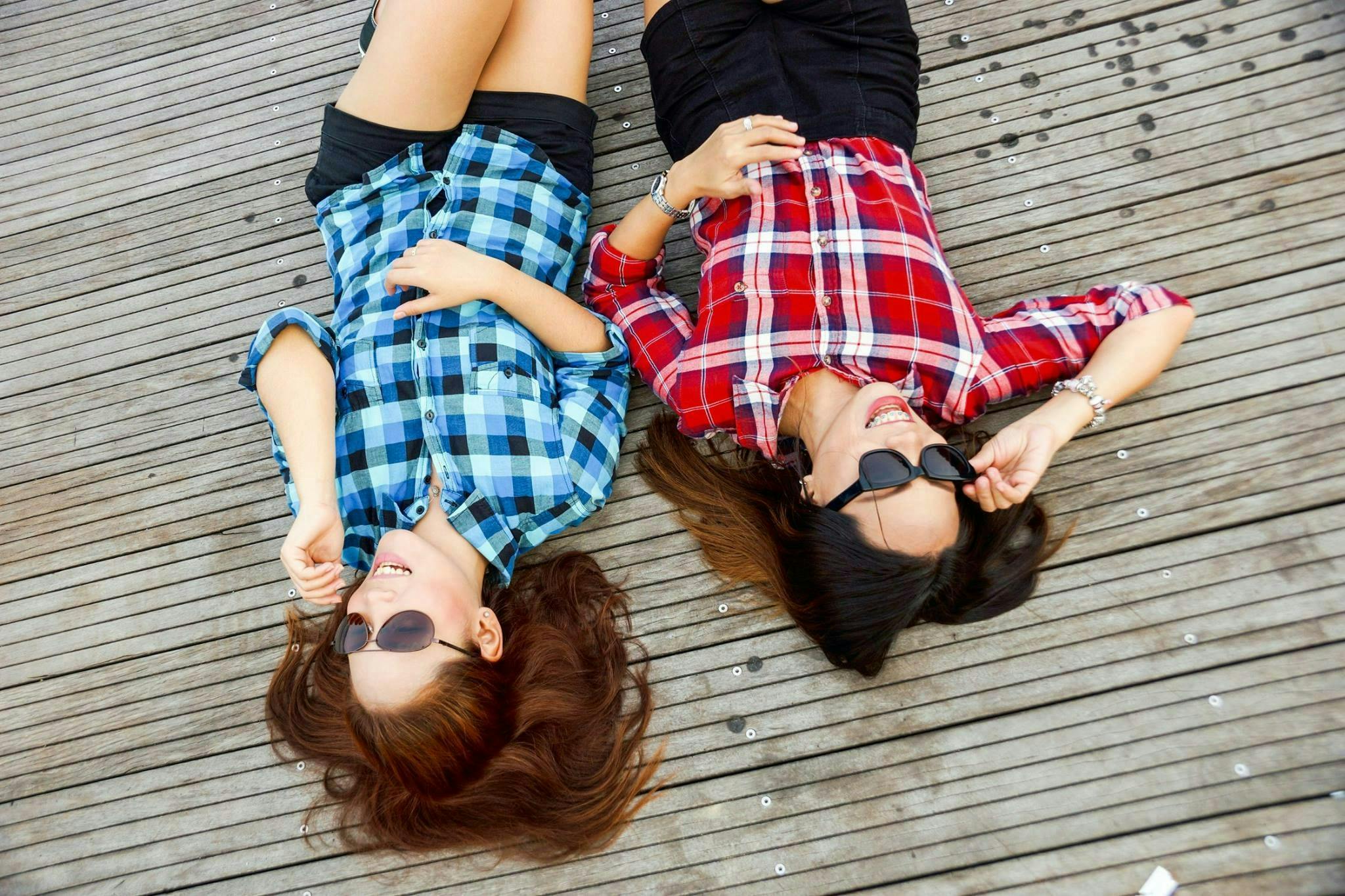 Two woman wearing summer fashion clothes while laying down. Two woman wearing summer fashion clothes while laying down.