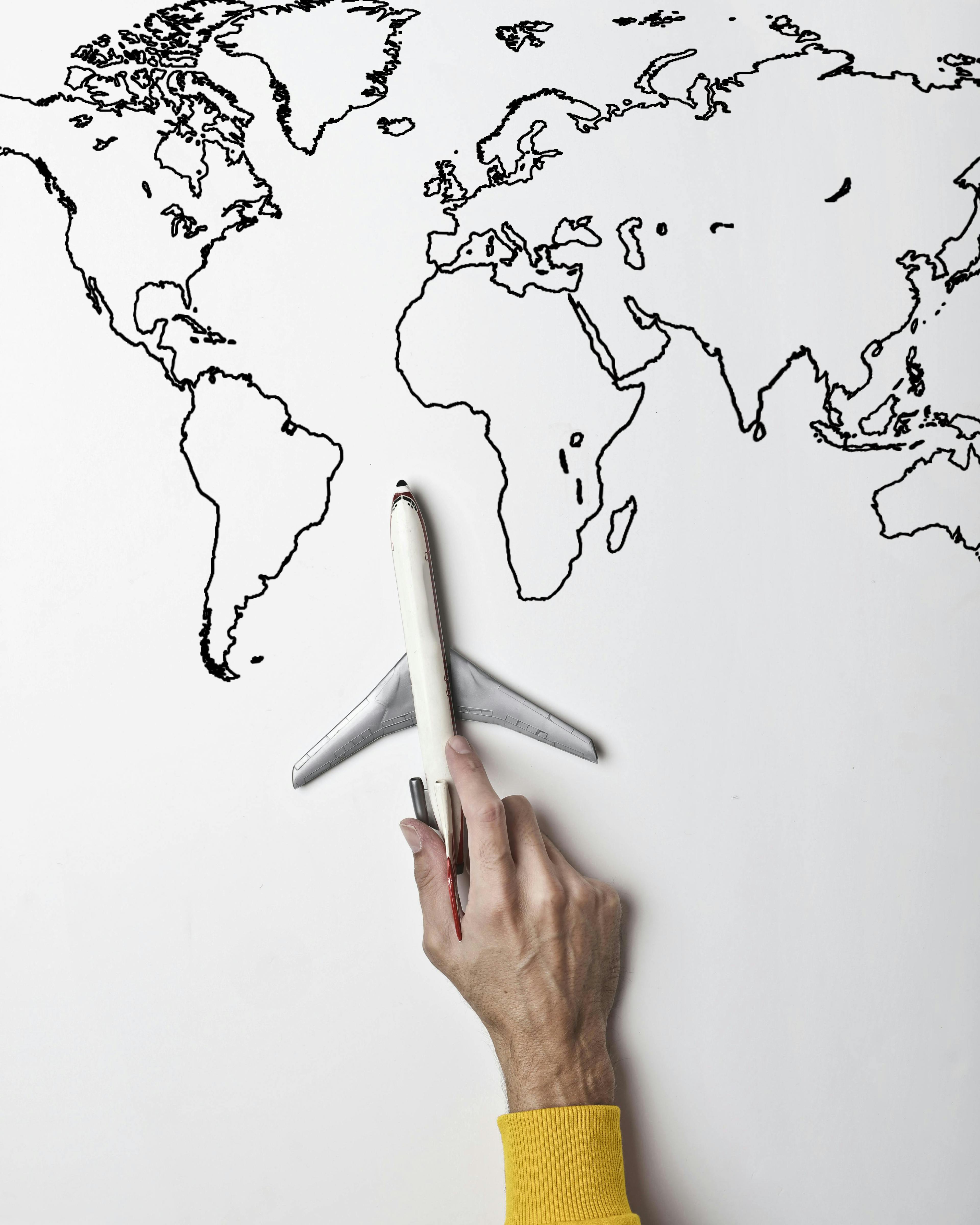 Person holding small toy airplane against black and white map Person holding small toy airplane against black and white map