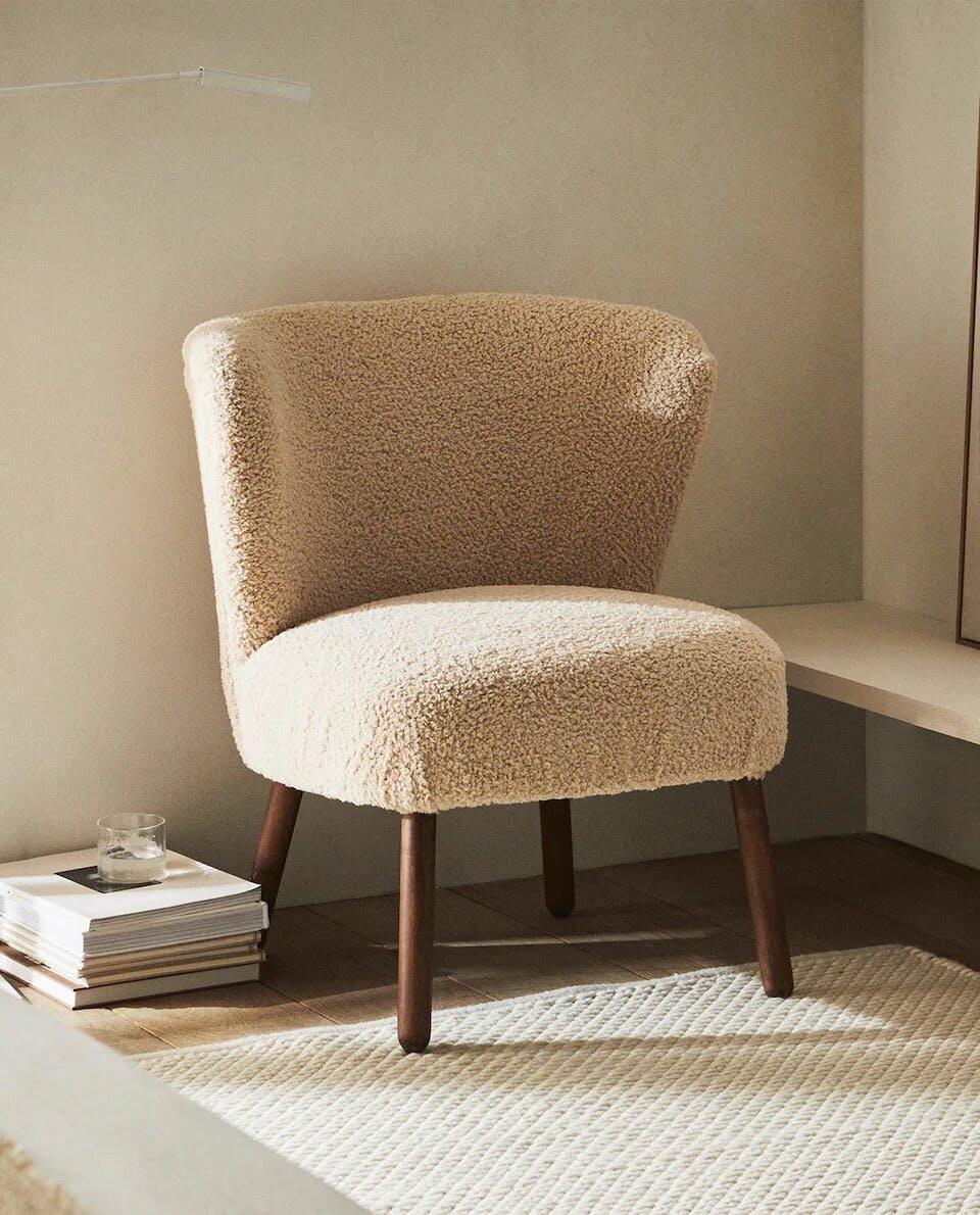 a upholstered chair next to a rug on the floor, in the style of beige