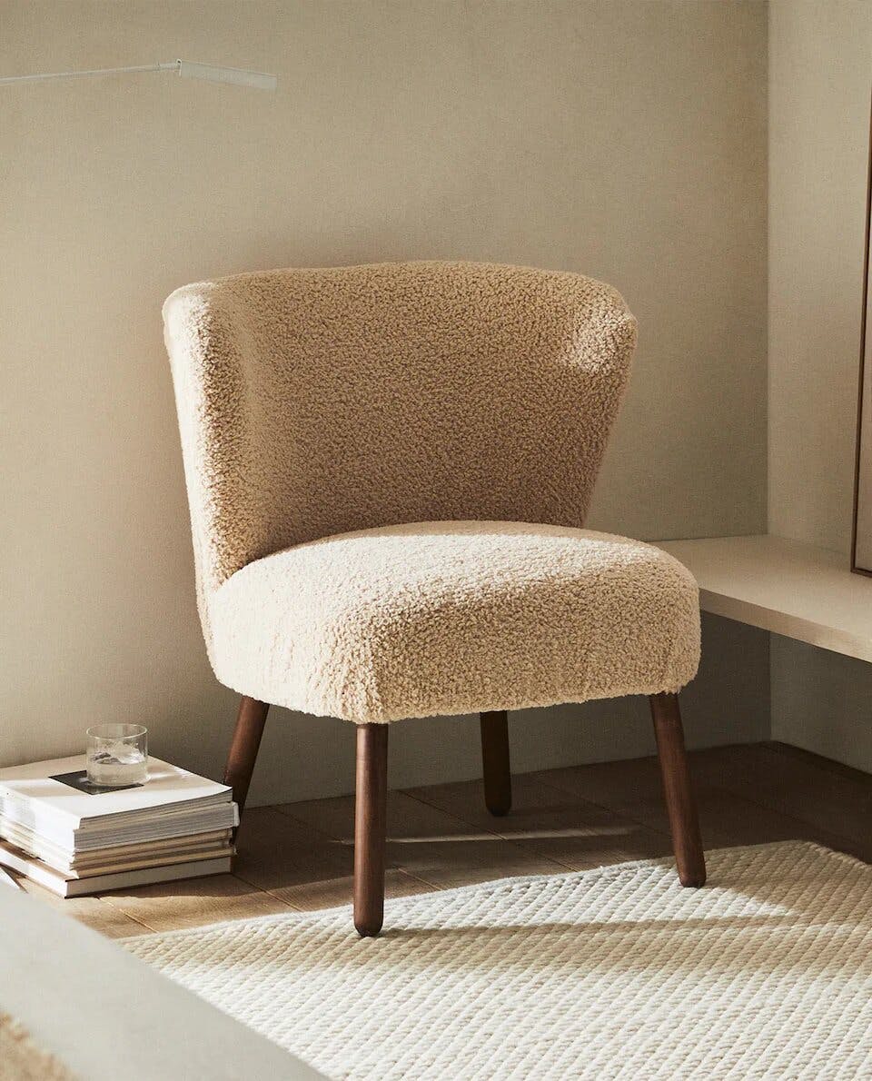 a upholstered chair next to a rug on the floor, in the style of beige a upholstered chair next to a rug on the floor, in the style of beige