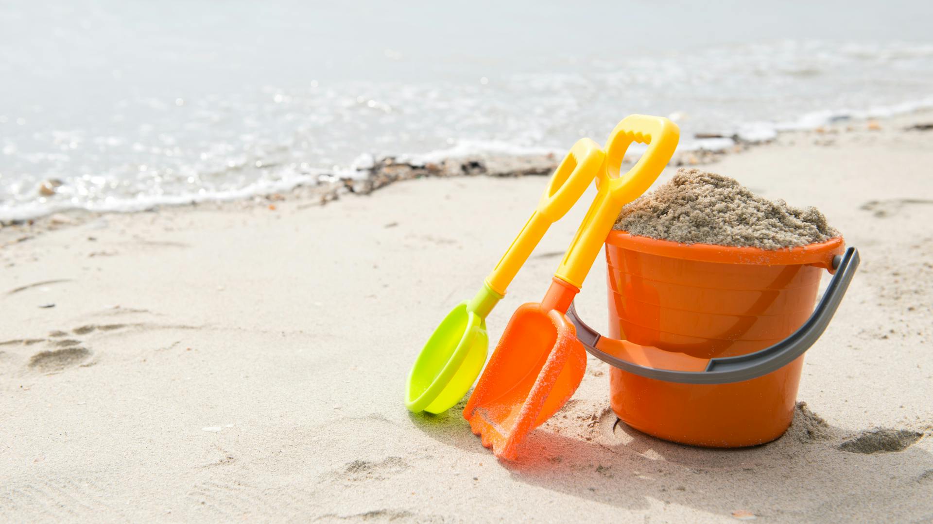 Kid's toys on a beach stuffed with sand.