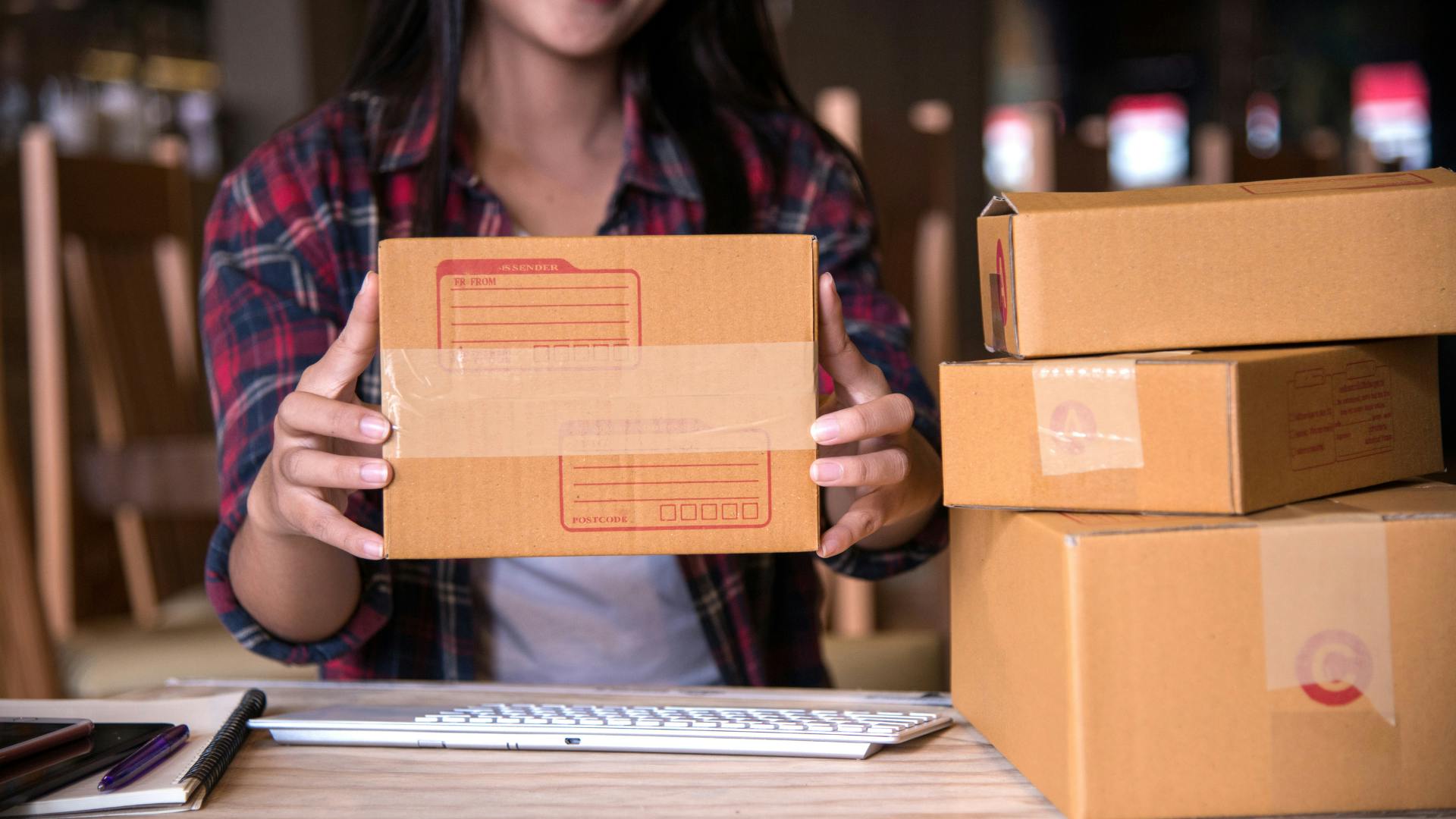 A woman showing a prepared shipping box. 