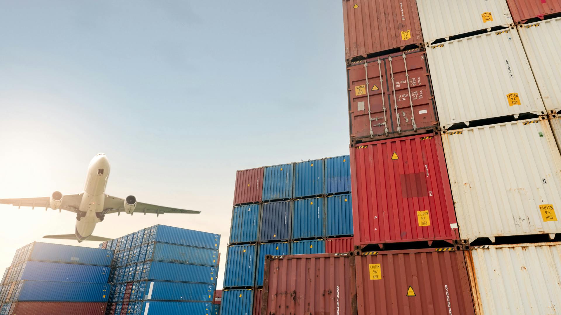 A plain flying over shipping containers.