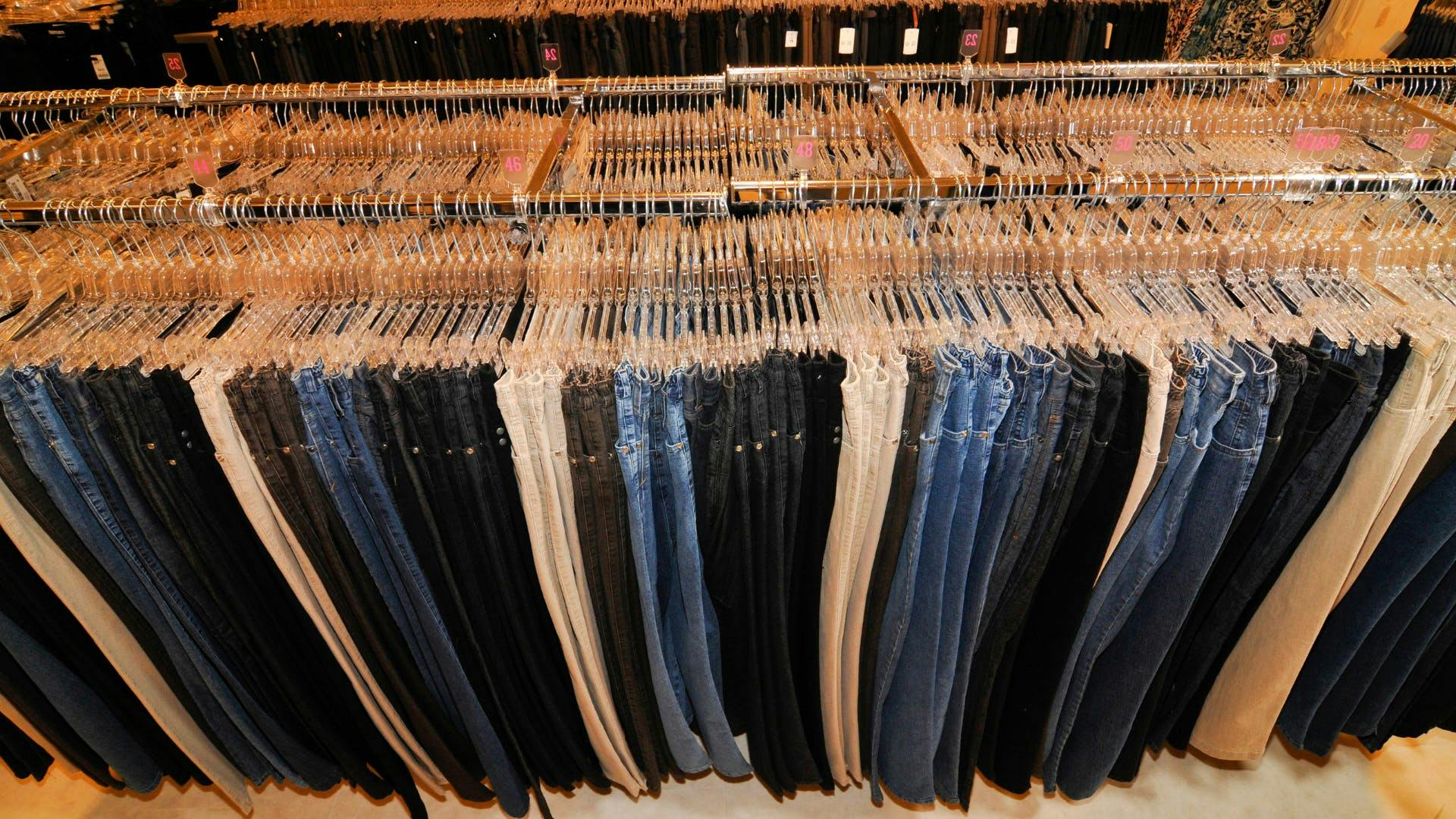 A retailer store clothing rack full of pants. 