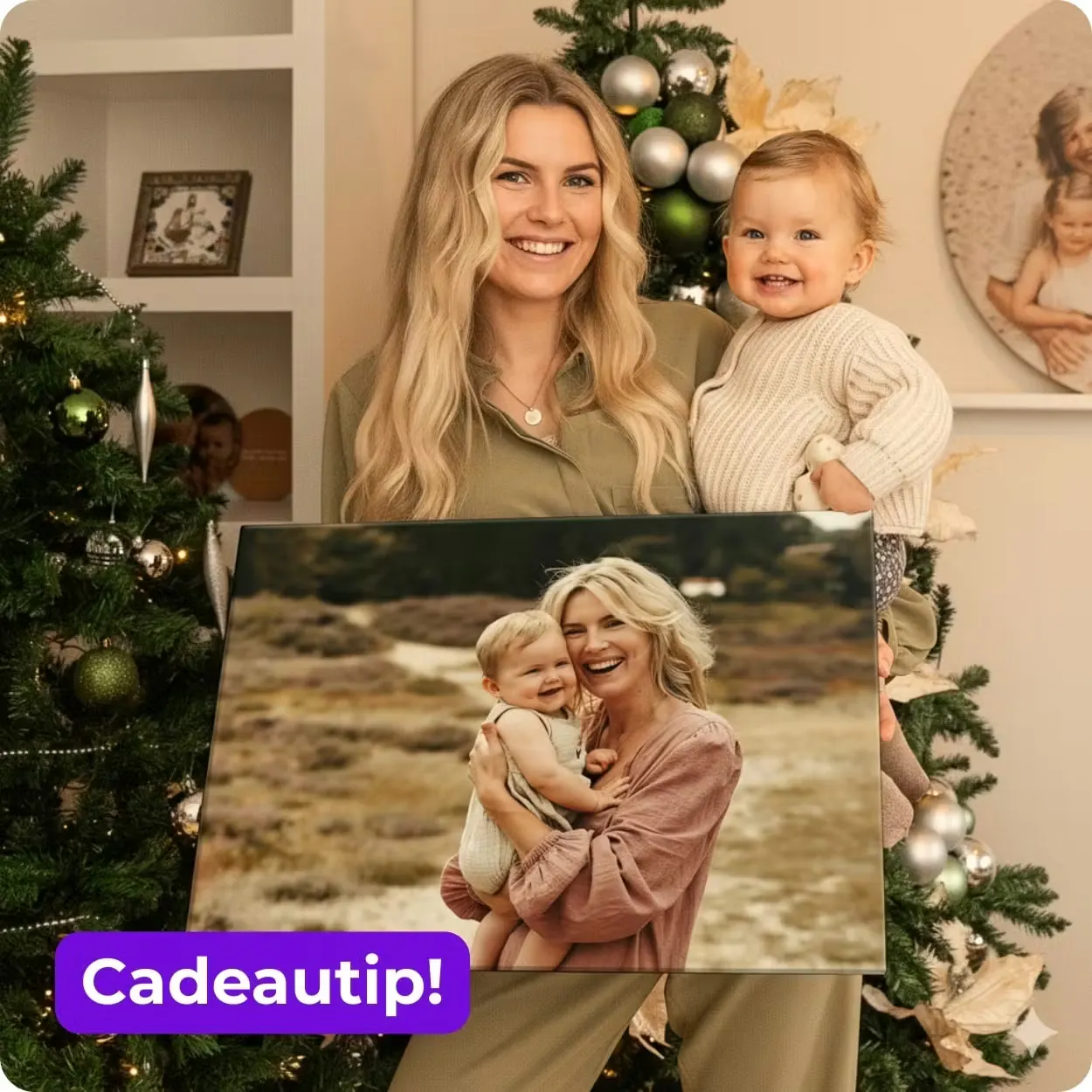 Foto op canvas; Een vrouw houdt de canvas vast in haar ene hand, waarop zij en een baby staan, en in haar andere hand de baby van de foto