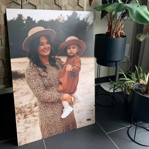 Een foto op aluminium van een vrouw die een baby vasthoud, waarbij zowel de vrouw als de baby een hoed op hebben