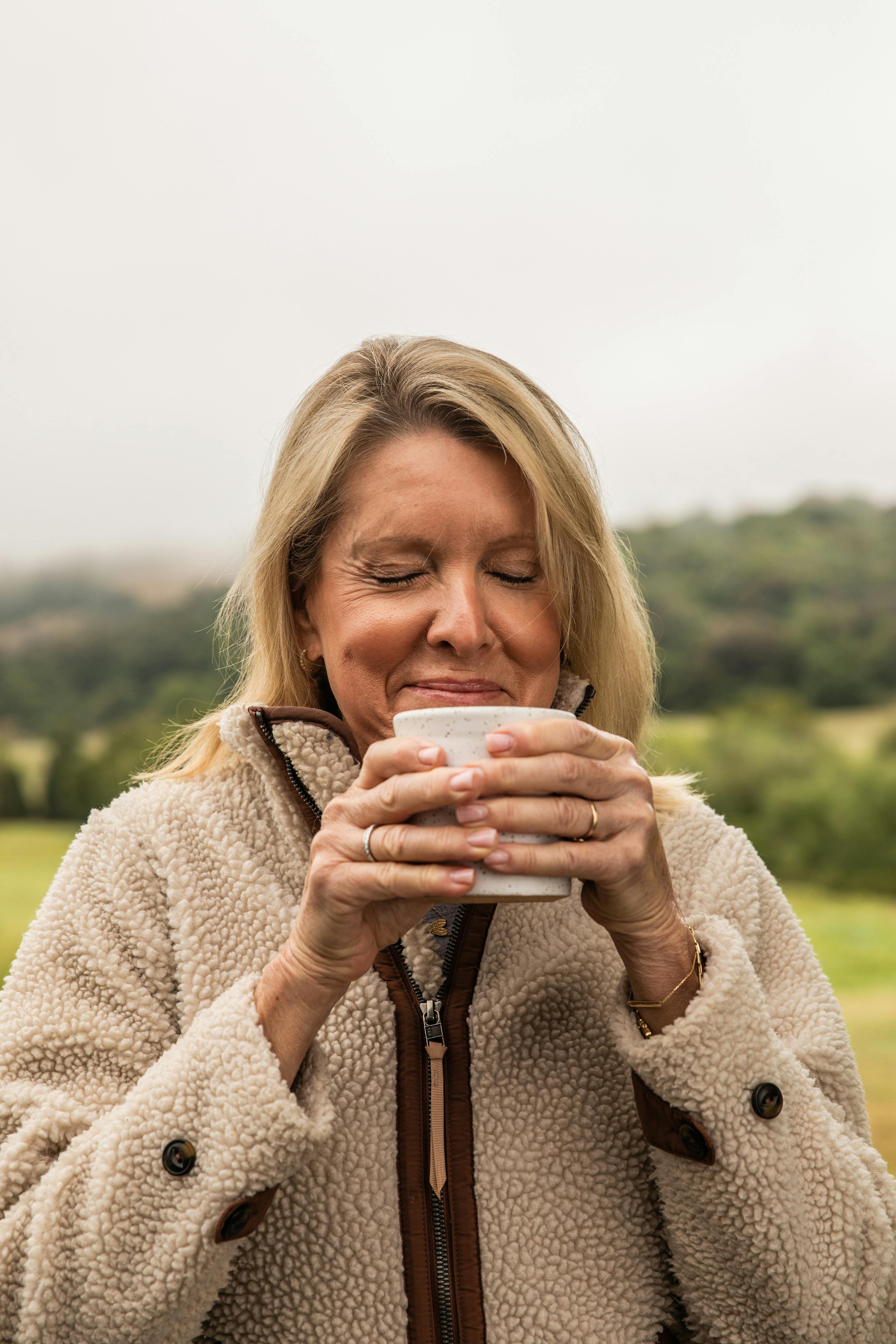 Woman delightfully drinks her warm morning beverage full of functional ingredients