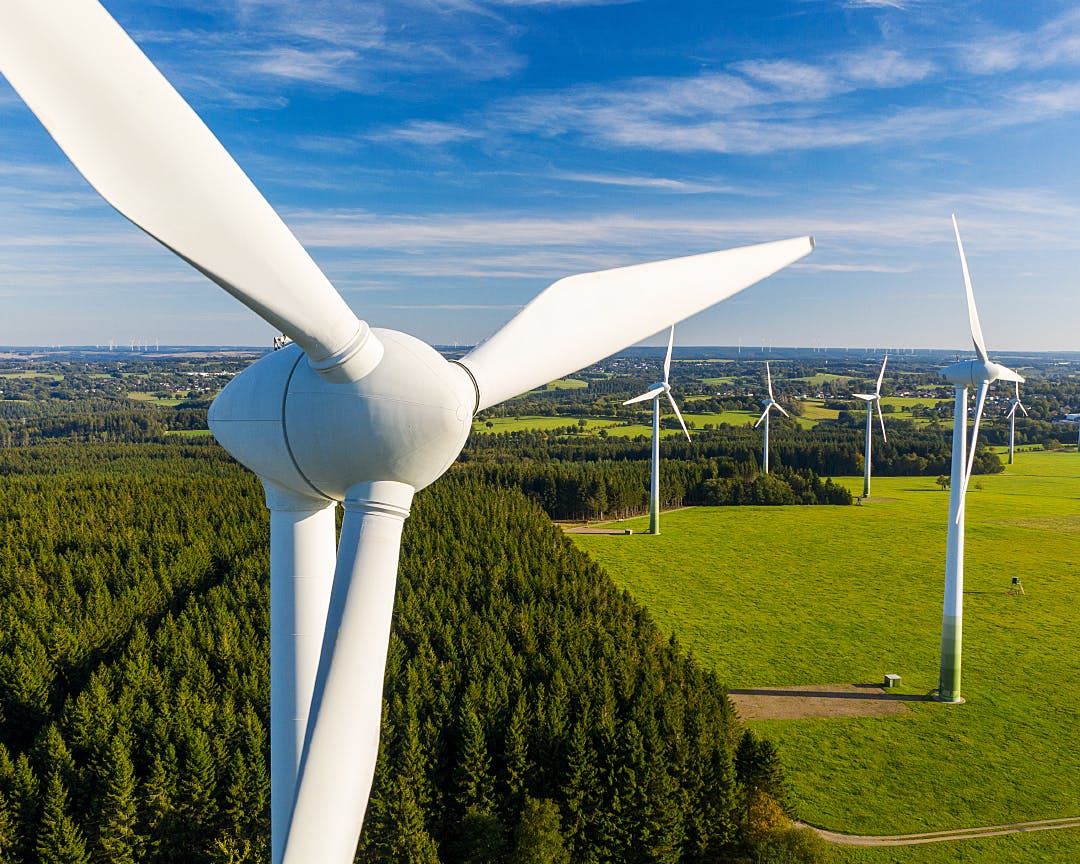 High angle view of six turbines in an onshore wind farm against a blue sky