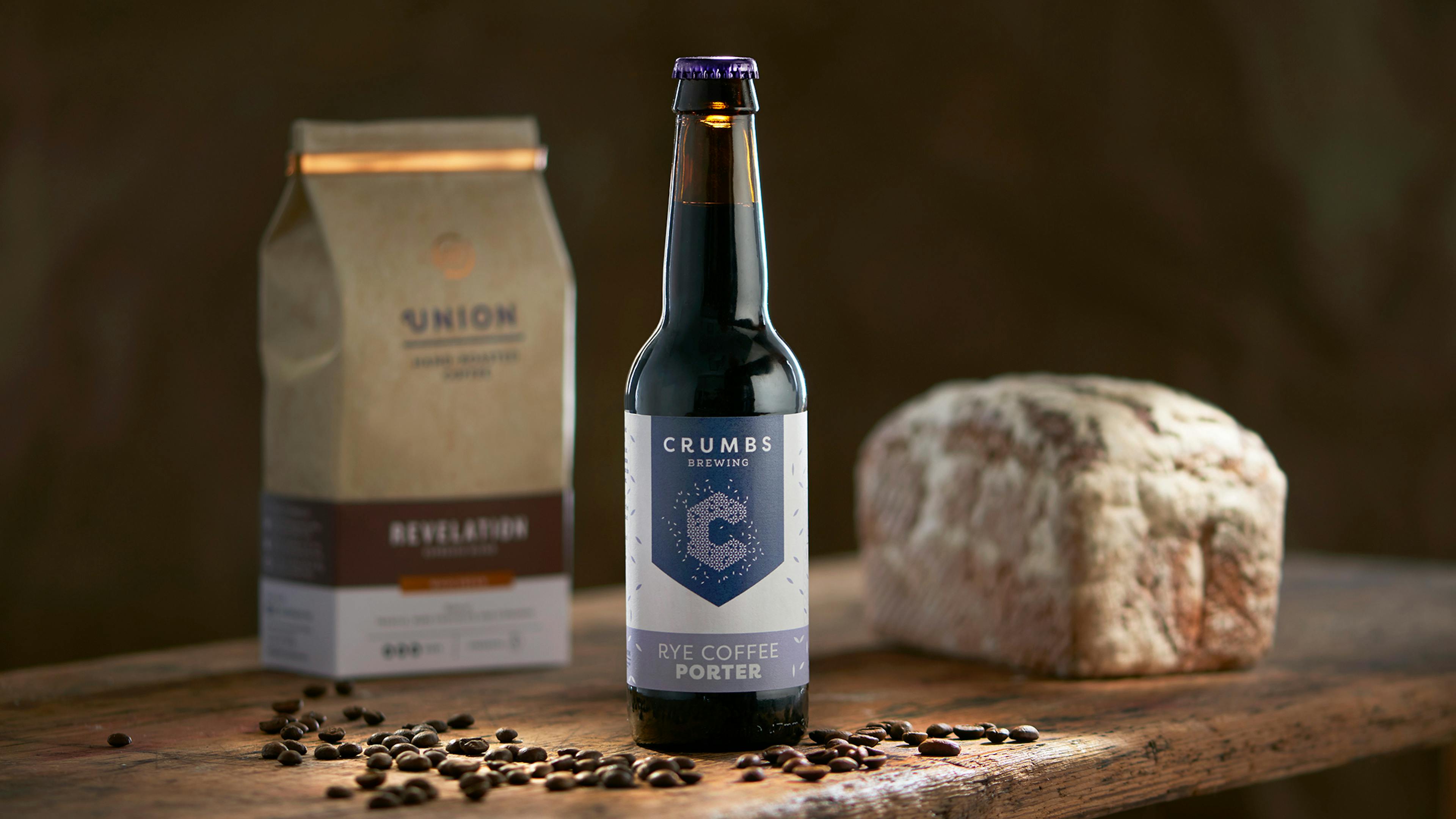 a Crumbs Rye Coffee Porter in-front of a loaf of bread and coffee bag