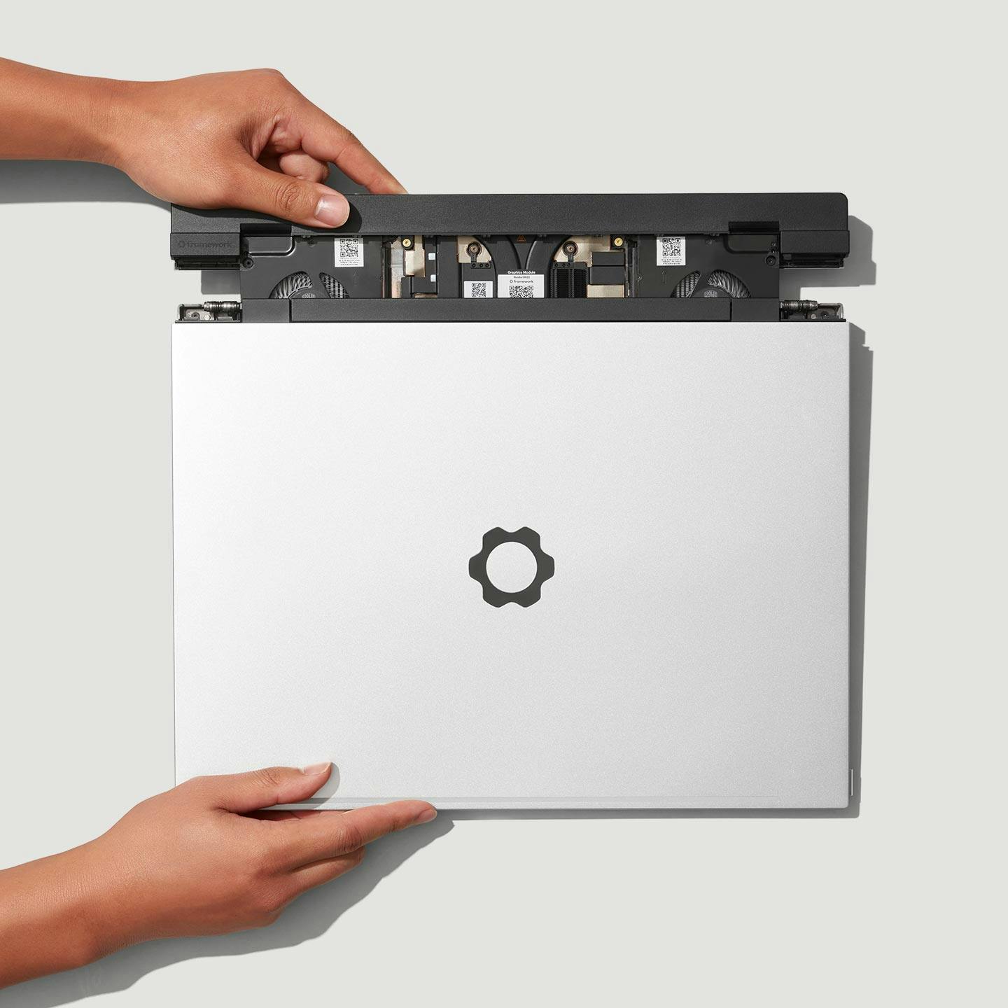 Top-down studio shot of a Framework Laptop 16 with hands installing the swappable GPU.