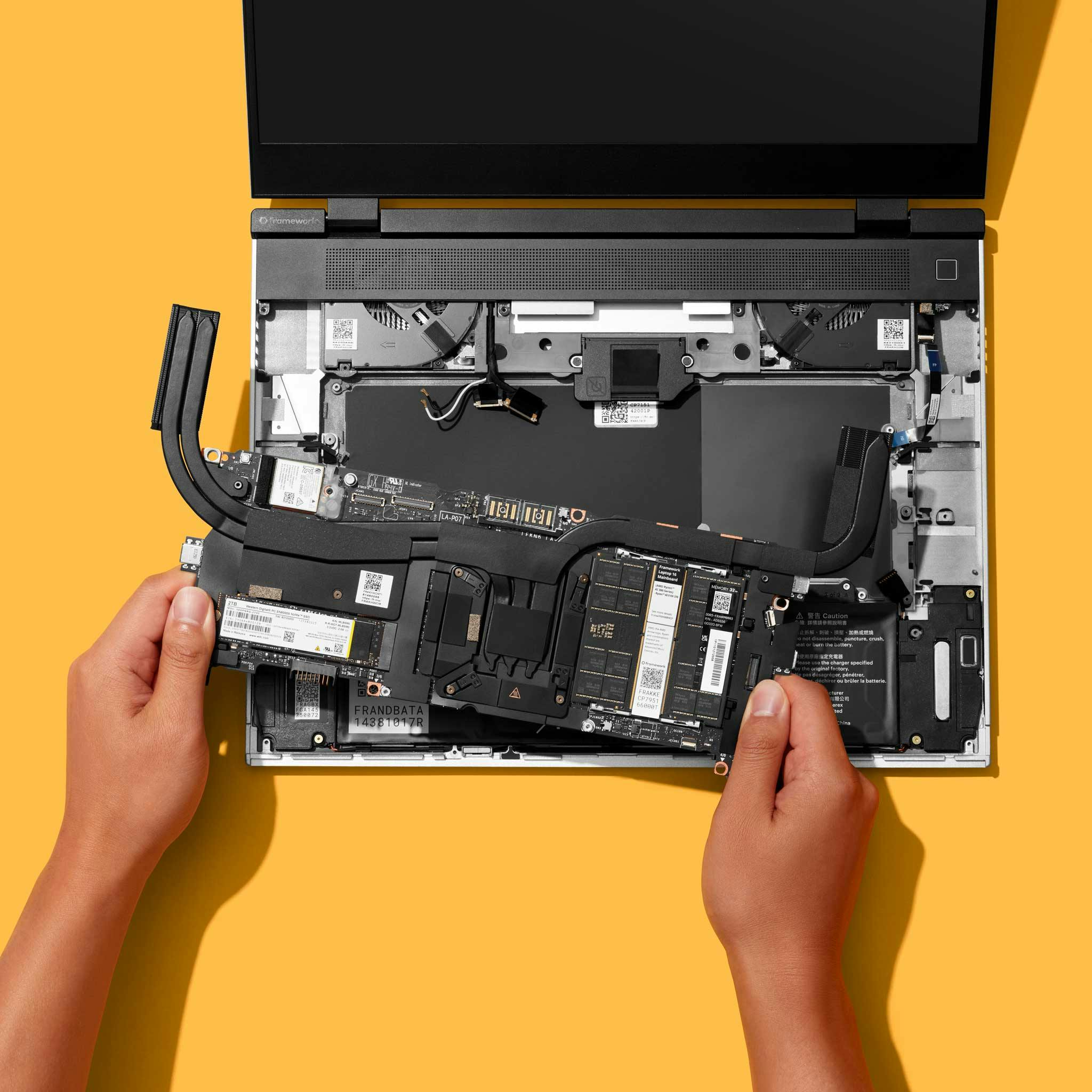 Top-down studio shot of a Framework Laptop 16 with a person installing the mainboard.