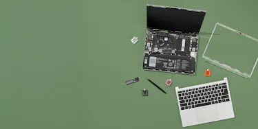 Framework Laptop 13 with bezel and top cover removed, exposing internals with Expansion Cards, screws and screwdriver beside it.