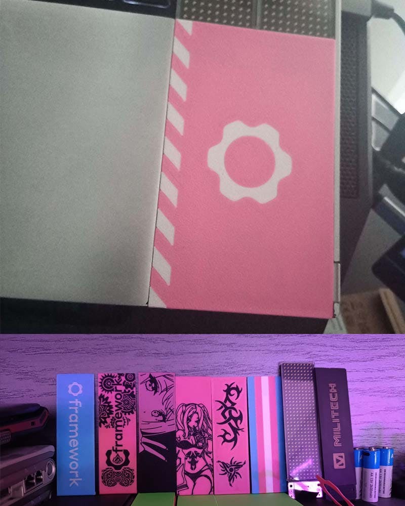 Close-up shot of custom 3D printed pink spacers for Framework Laptop 16, accompanied by a large stack of different kinds of 3D printed spacers.