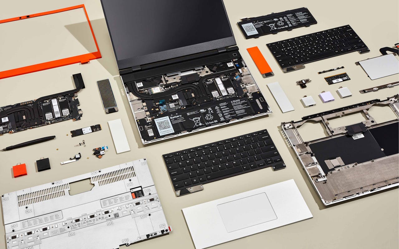Top-down studio shot of a disassembled Framework Laptop 16.