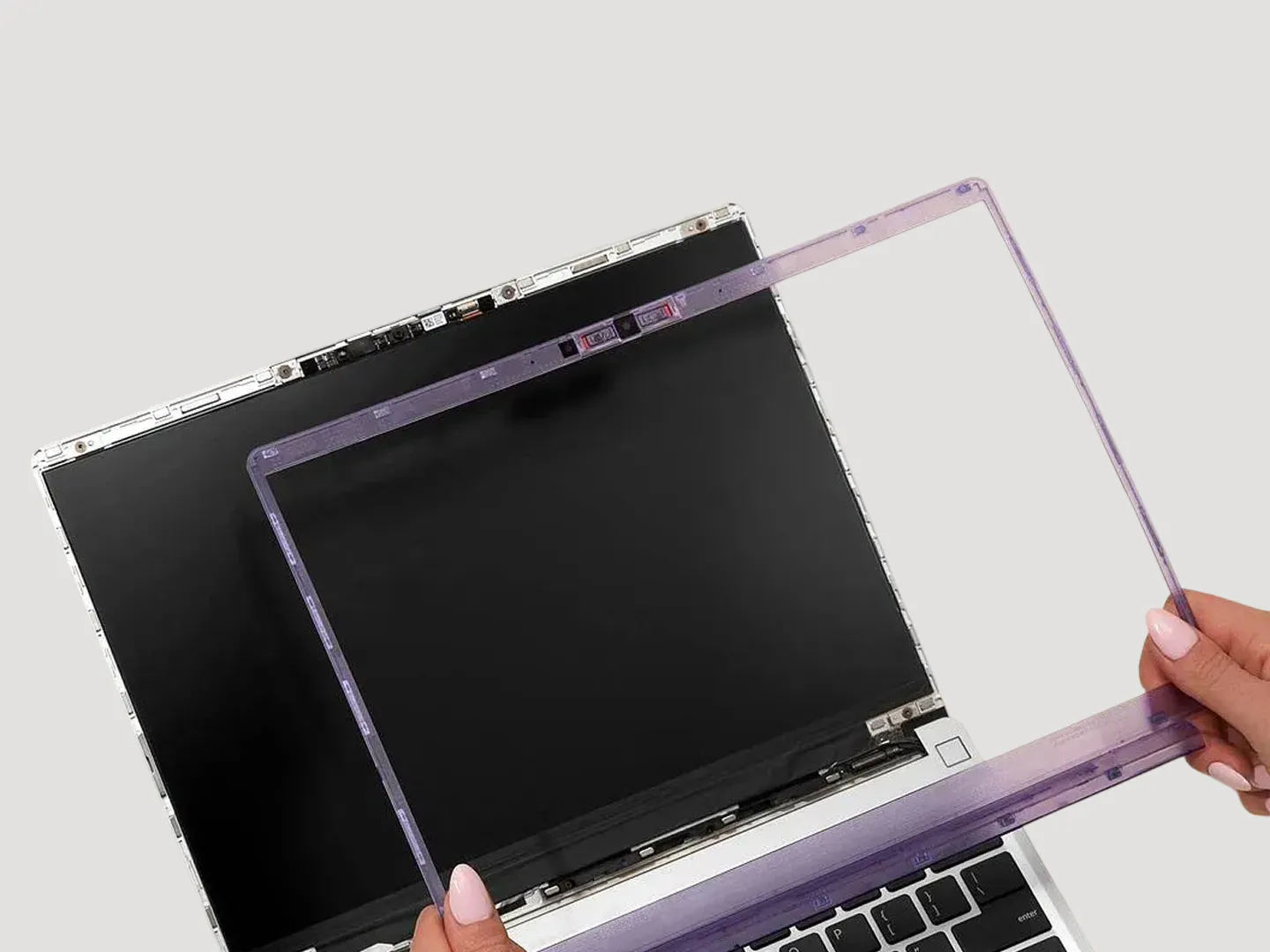 A purple translucent bezel being installed on a Framework Laptop 13