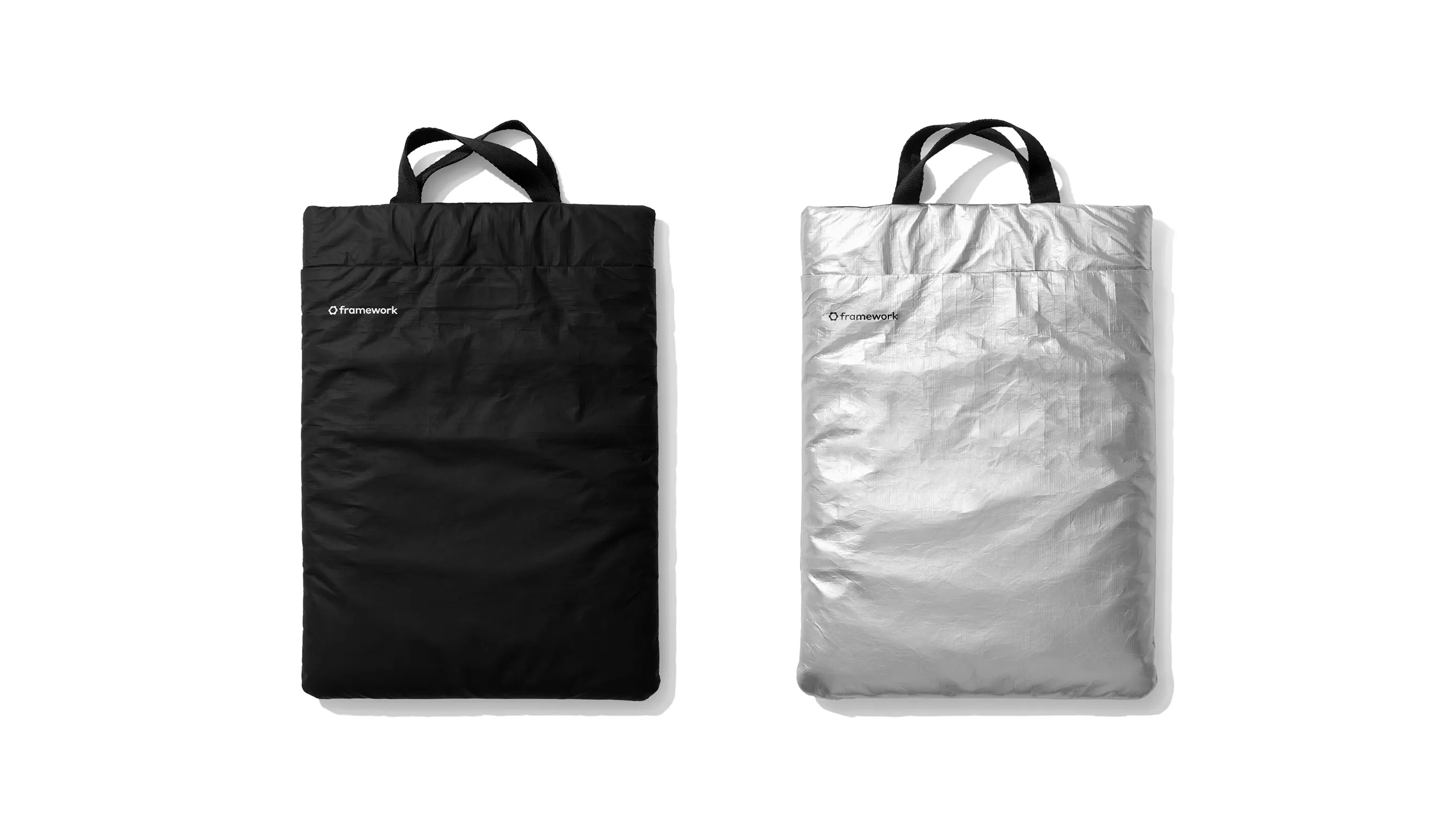 A top-down studio shot of two Framework laptop sleeves, one in black and the other in metallic silver.