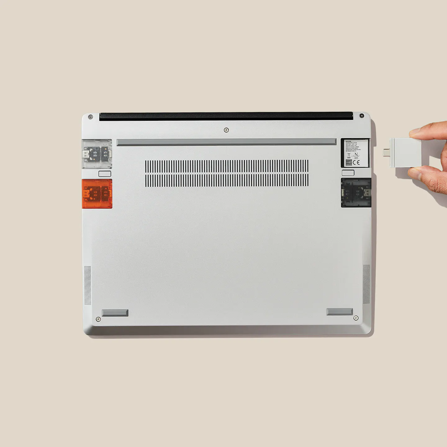 A top-down studio shot of an upside down Framework Laptop 13 showing expansion cards installation. 