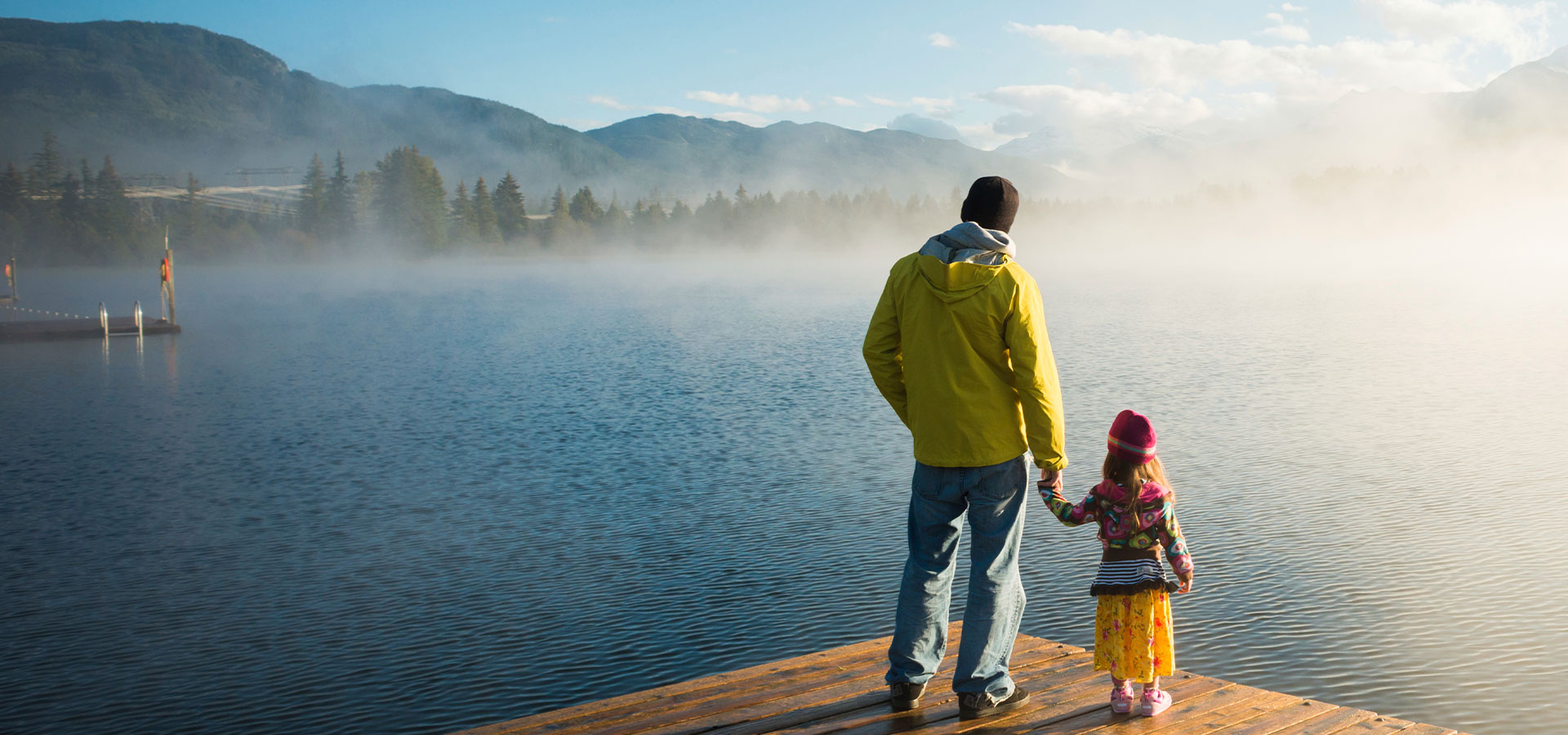 Man and child standing by the lake on a pier