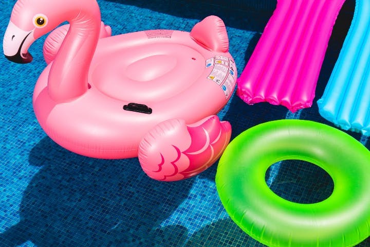 pink toy duck and other inflatables floating in a pool