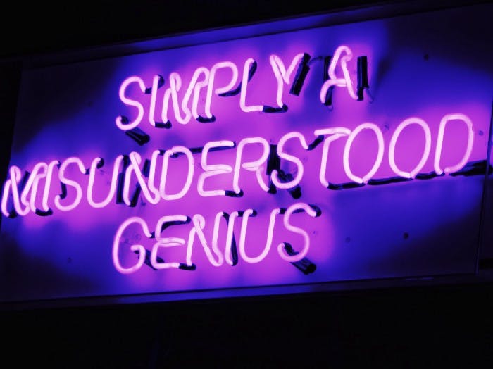 A neon sign stock photo with text: "Simply a Misunderstood Genius"