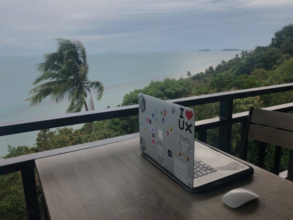 Picture of laptop in hill-top restaurant with views of the sea, mountains and palm trees