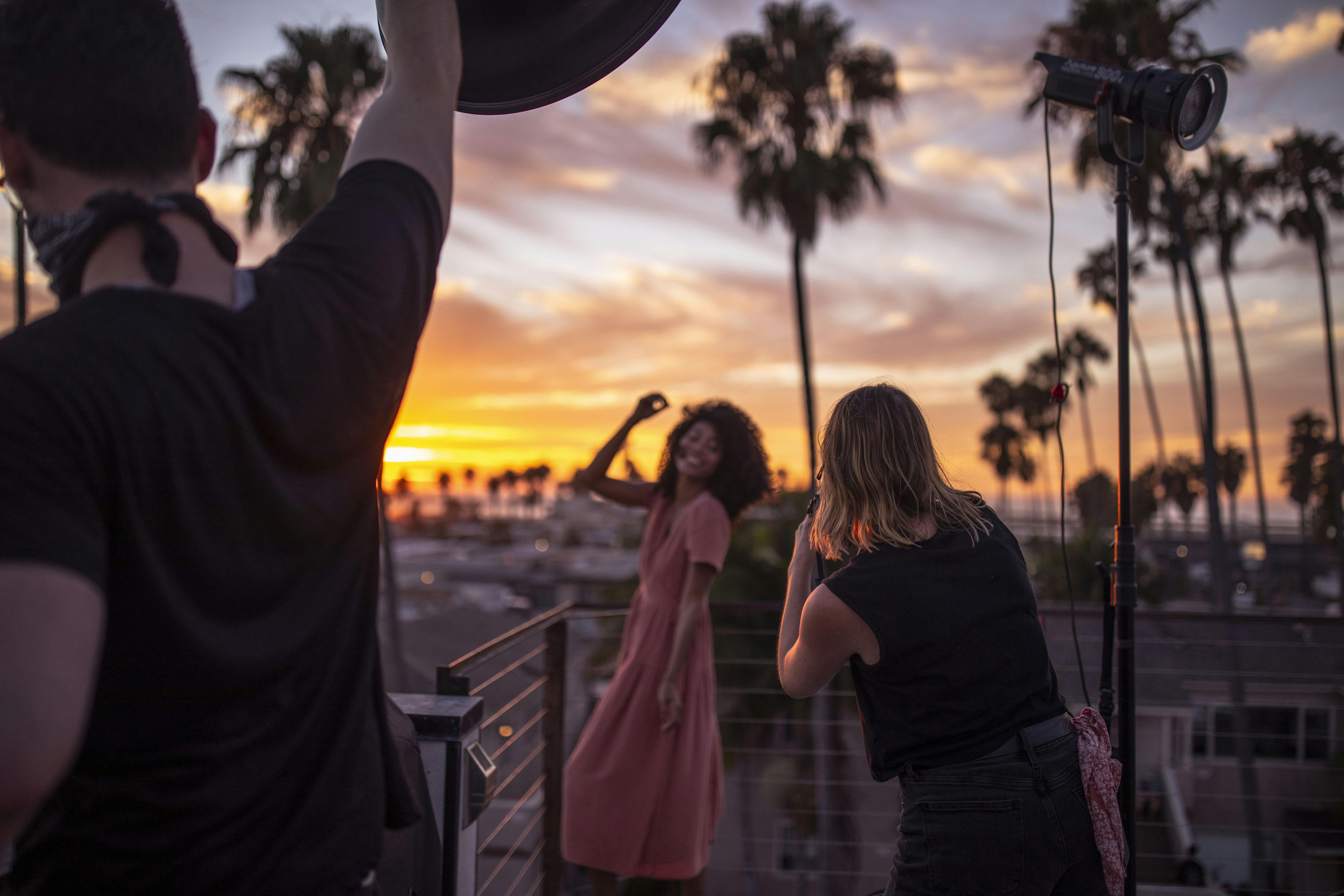 Girl posing in front of sunset and palm trees on a deck