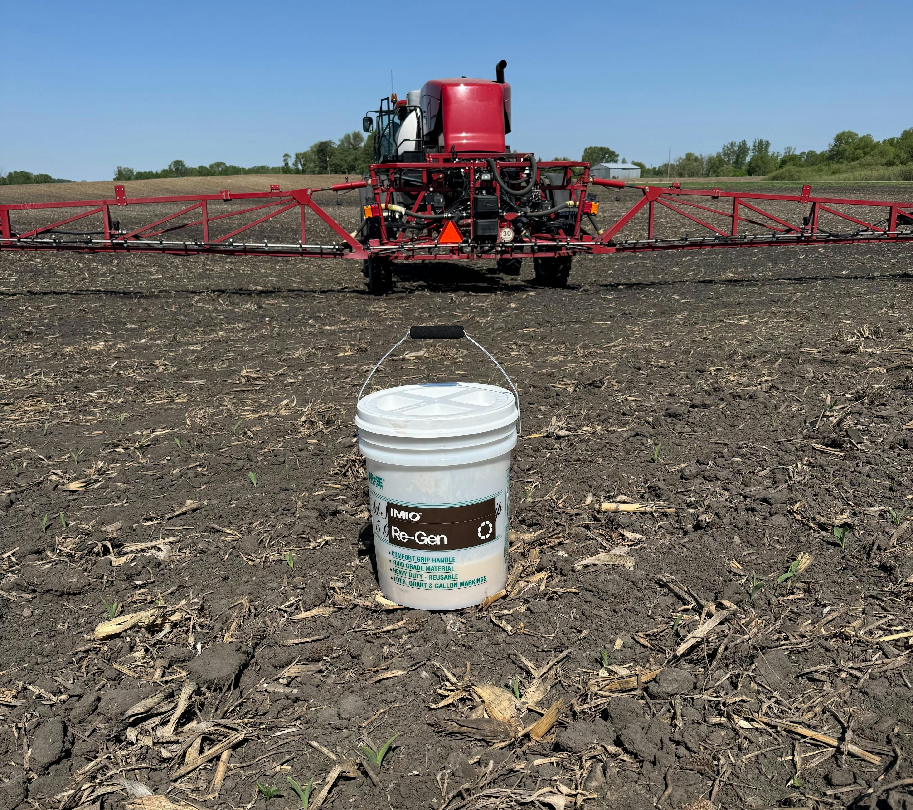 A bucket of Re-Gen in a field of crop residue.