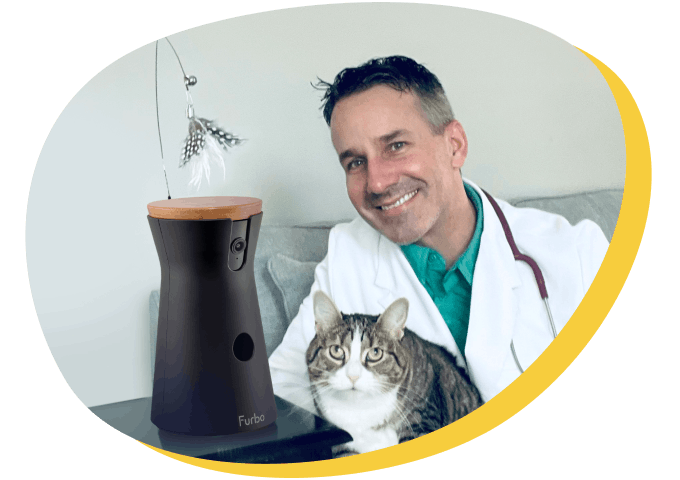 A veterinarian smiling beside a Furbo cat camera and a cat.