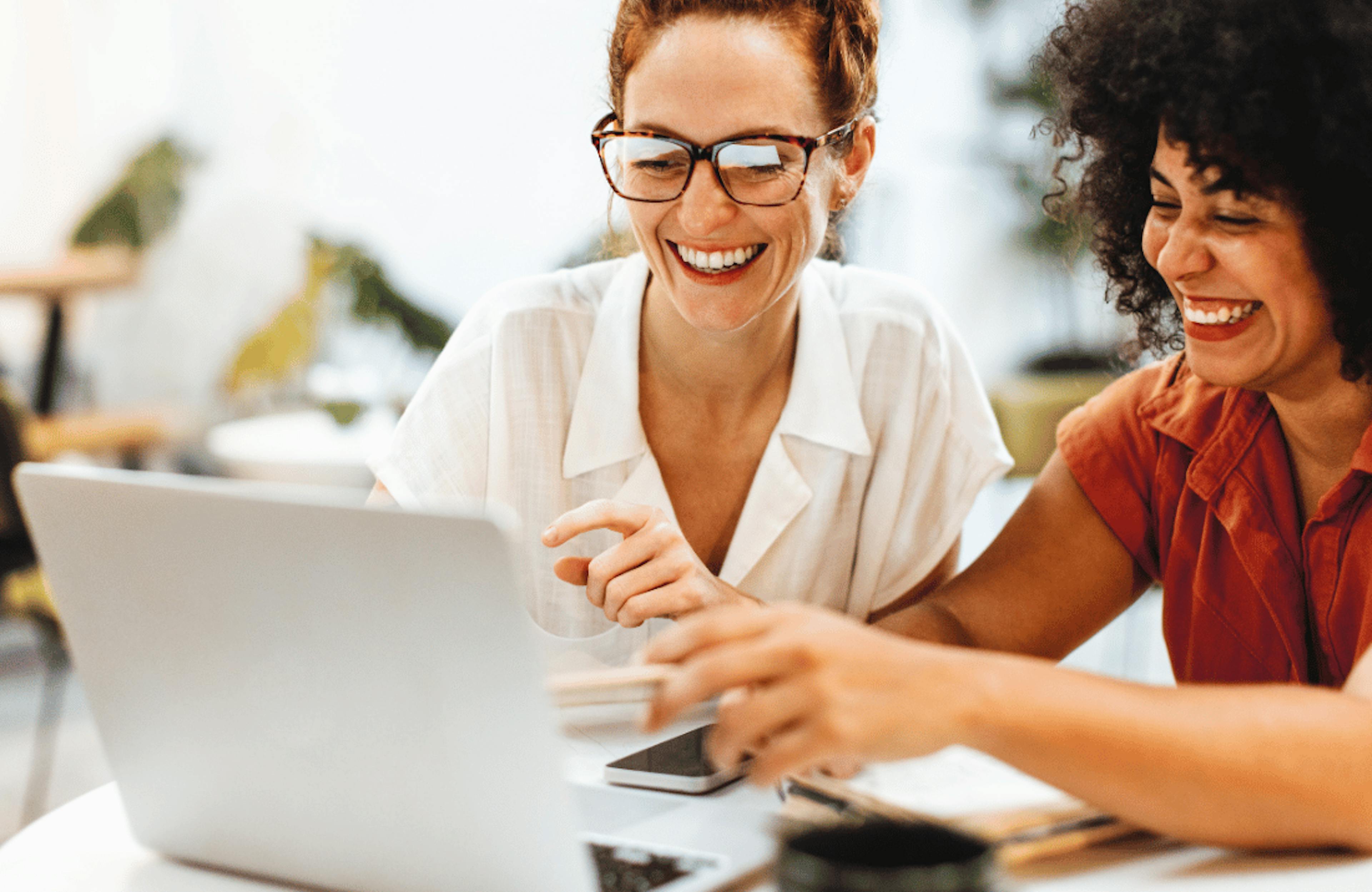 Co-workers have a laugh at some work on their laptop - Business broadband from Future Connected Fibre