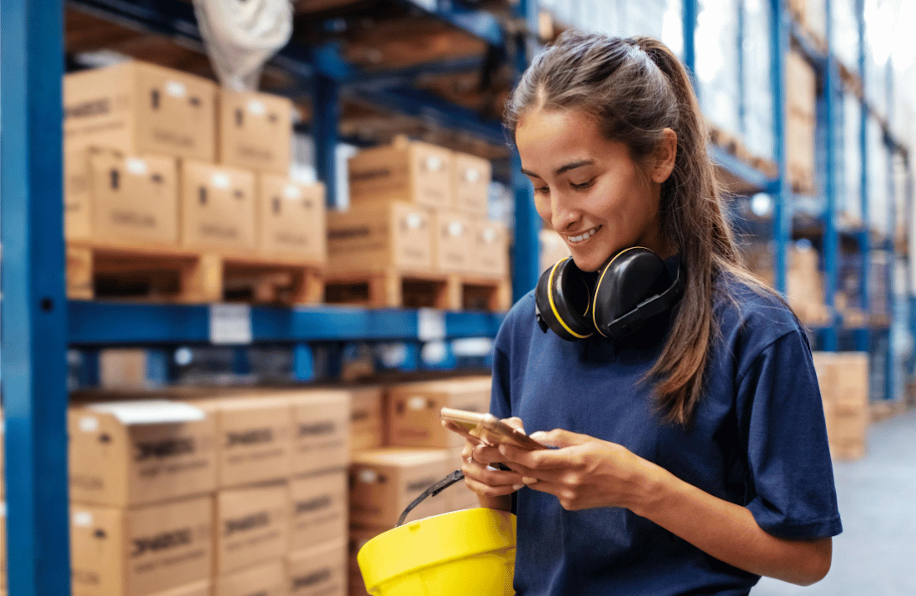 Woman reviews order on mobile device in warehouse