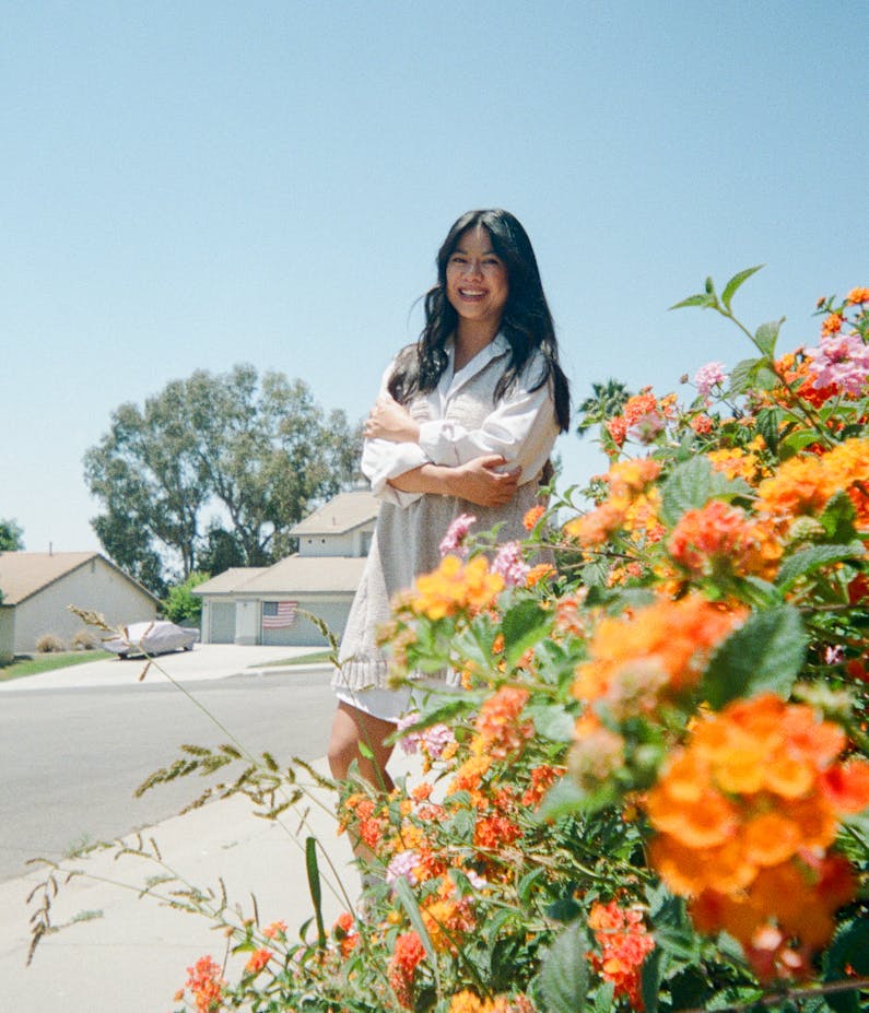 Mytho Vo, Project Manager, standing in front of some bright orange flowers
